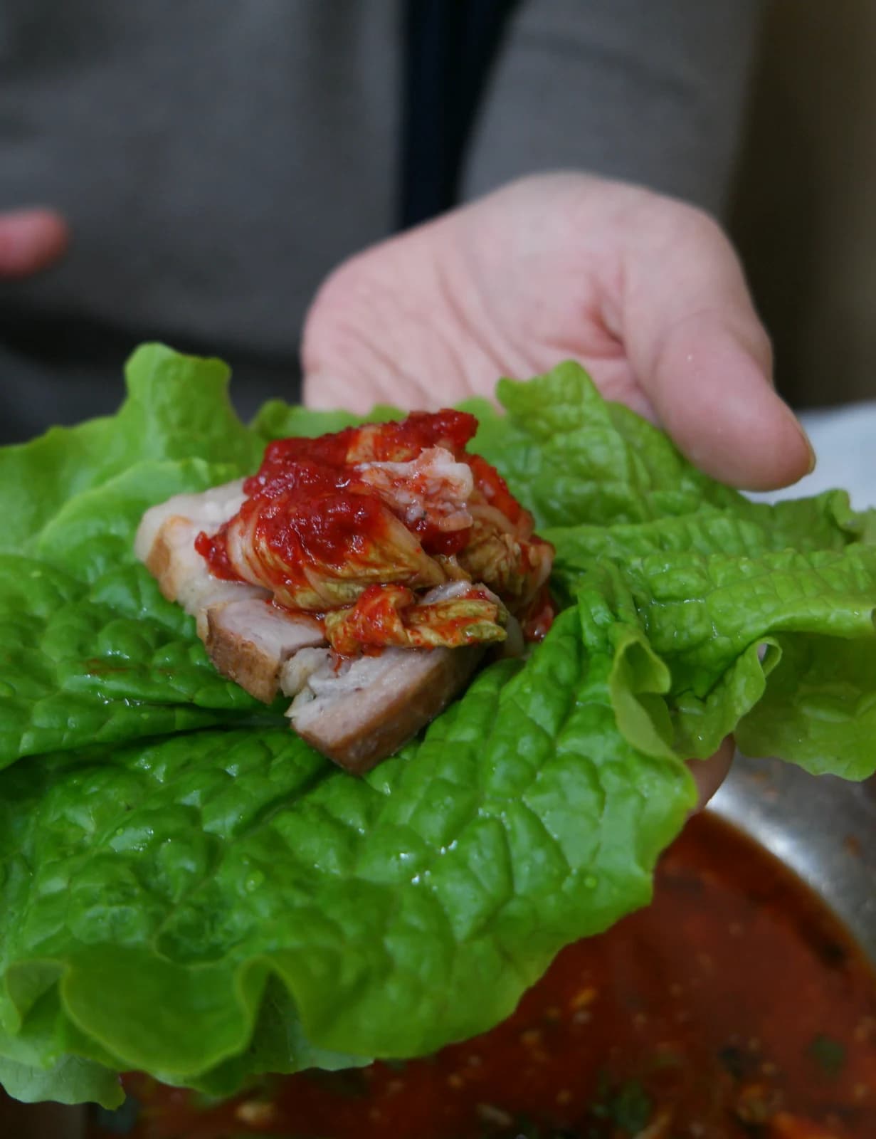Lettuce wrap with bossam pork and red bossam kimchi ready to eat in one bite