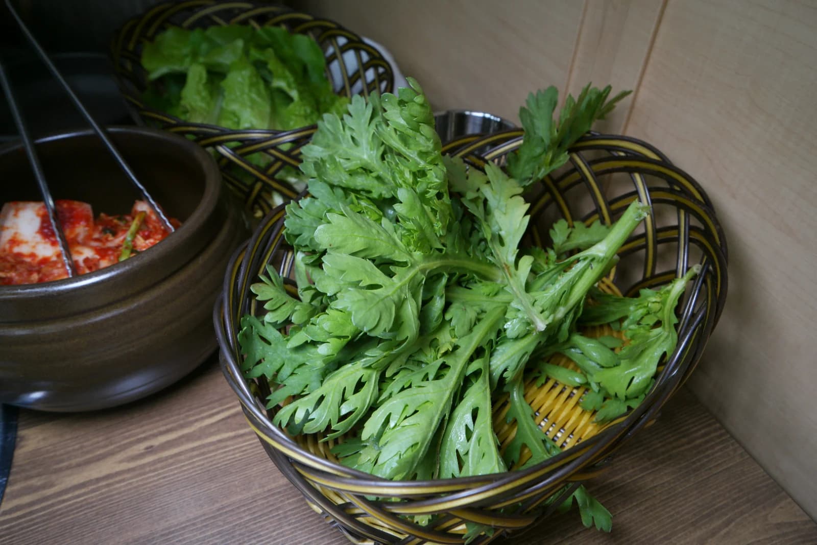 Basket of fresh crown daisy greens served as a wrap vegetable