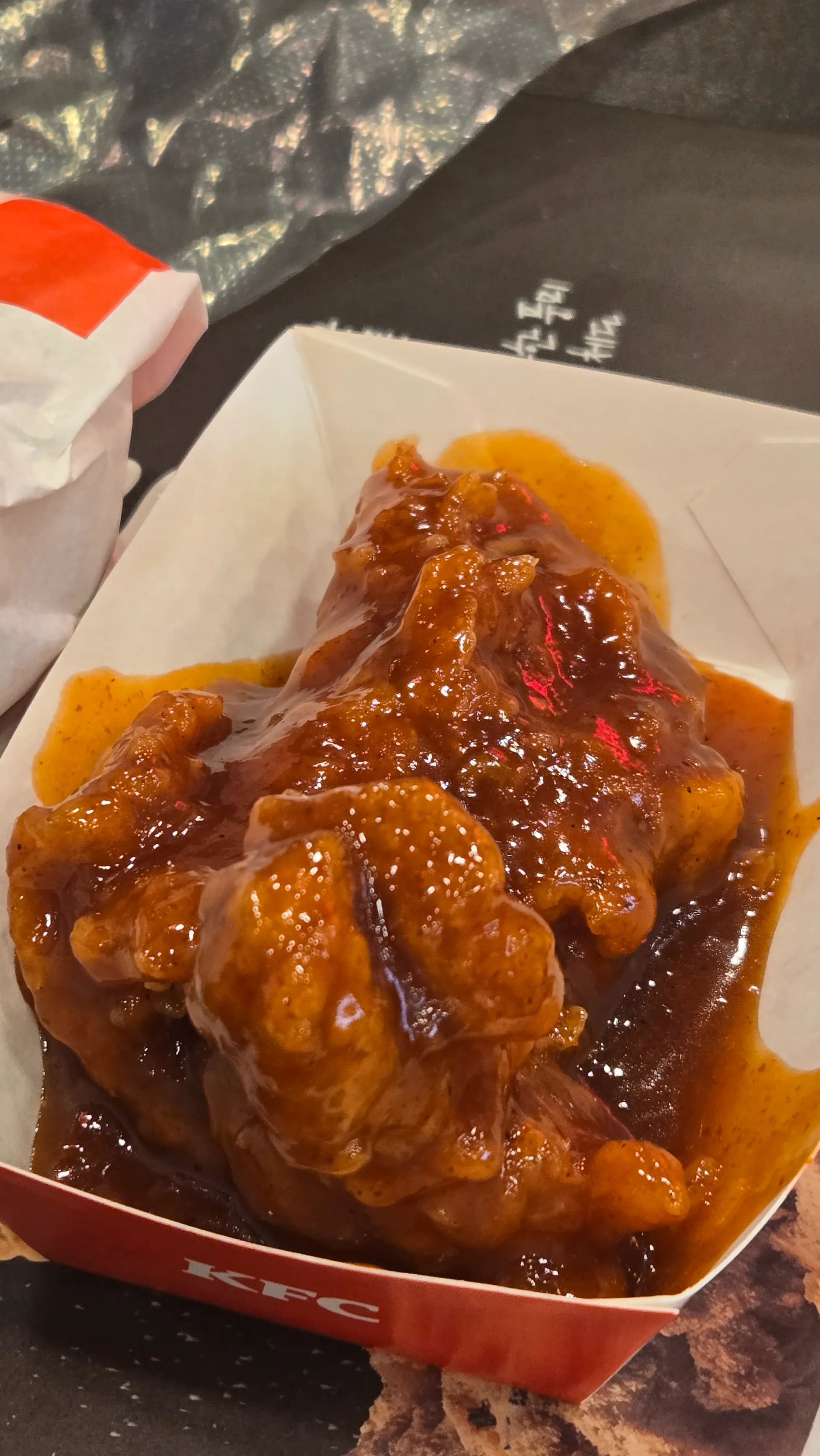 한국 KFC 갓양념치킨 클로즈업 윤기 흐르는 갈색 양념 소스와 빨간 고추 조각