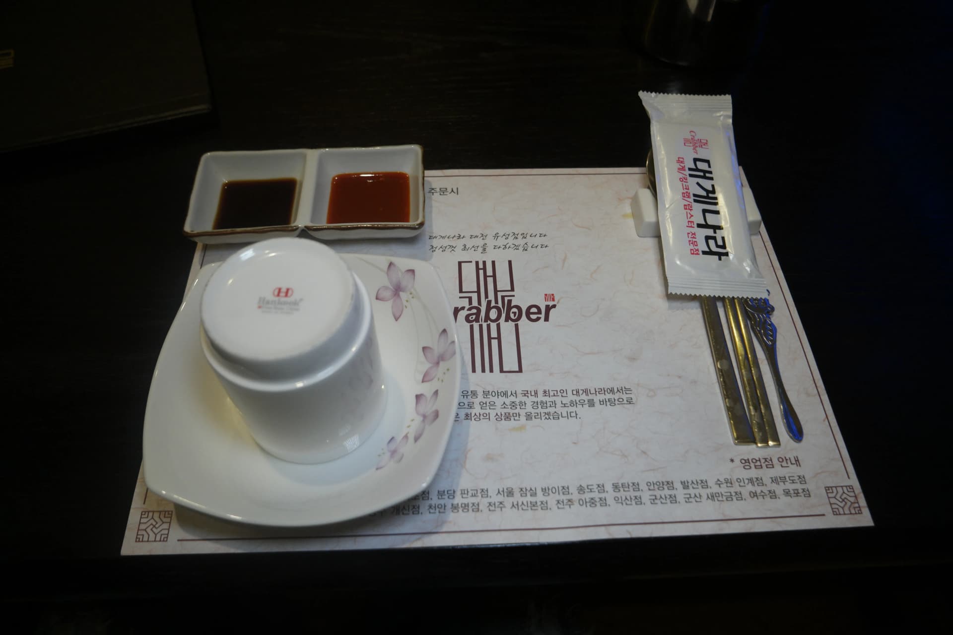 Mesa preparada en un restaurante de cangrejo real con gachas, ensalada, salsas y cubiertos perfectamente dispuestos | 하이제이에스비