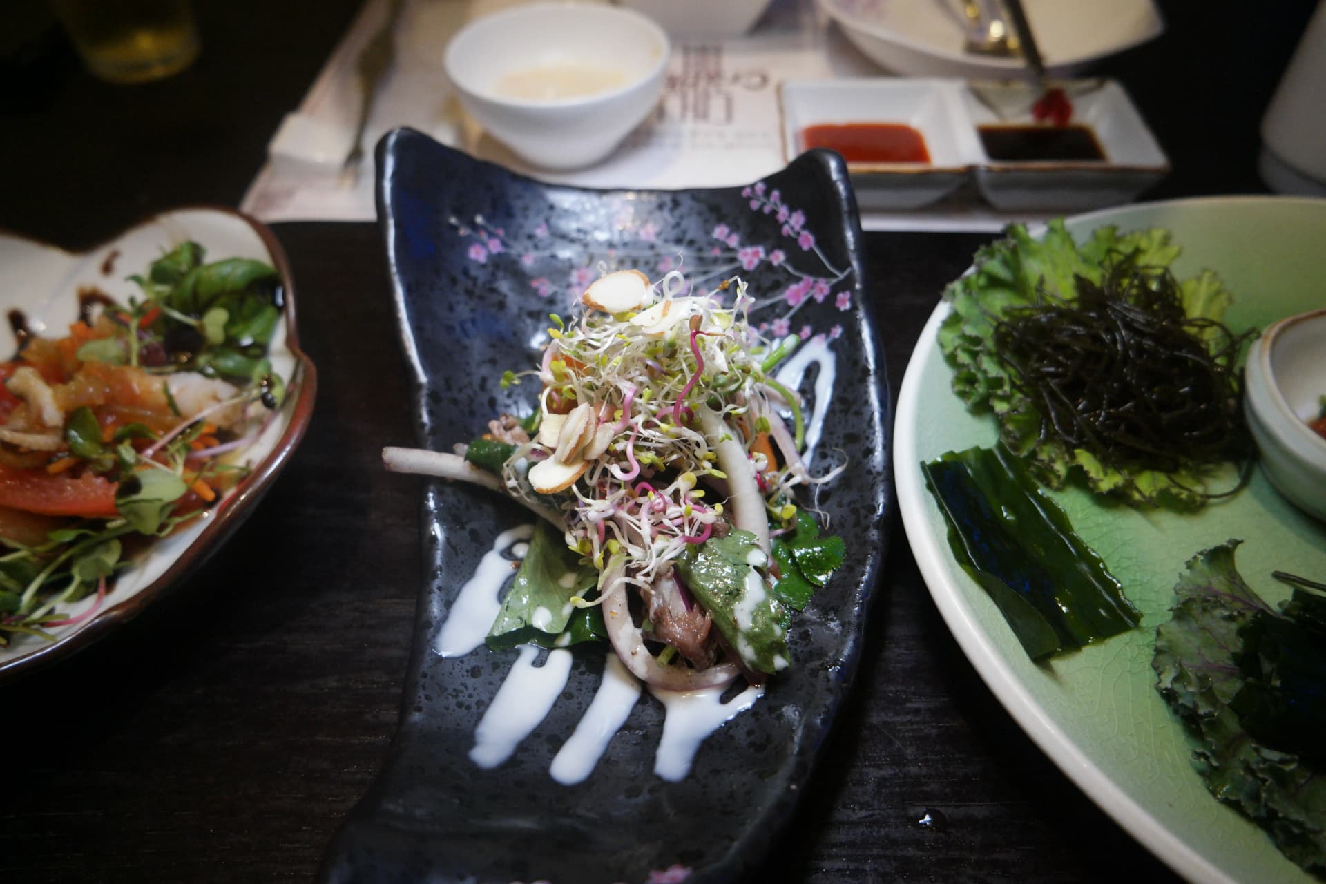 Primer plano de ensalada de brotes tiernos con almendras laminadas y aliño blanco cremoso por encima | 하이제이에스비