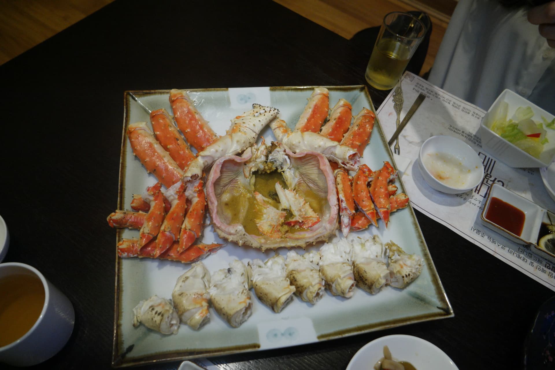 Cangrejo real entero cocido al vapor y preparado para comer, mostrando el caparazón con mantequilla de cangrejo, patas rojas y carne del cuerpo cortada en trozos | 하이제이에스비