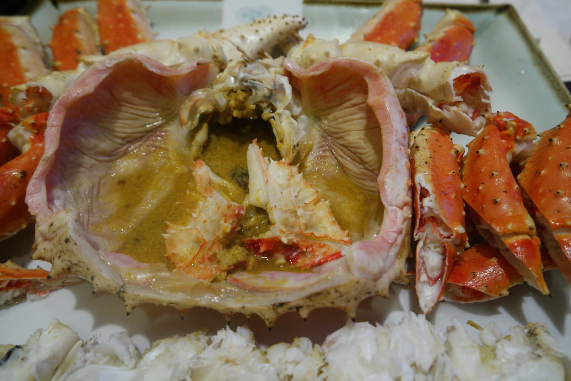 Primer plano de la mantequilla de cangrejo dorada y cremosa dentro del caparazón del cangrejo real | 하이제이에스비