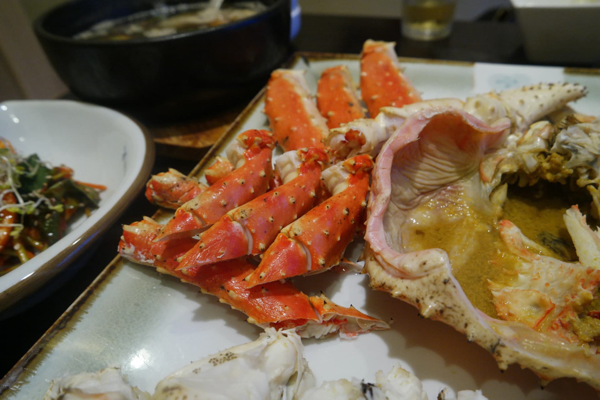 Vista general de la mesa con el cangrejo real al vapor y todos los acompañamientos creando una mesa abundante | 하이제이에스비