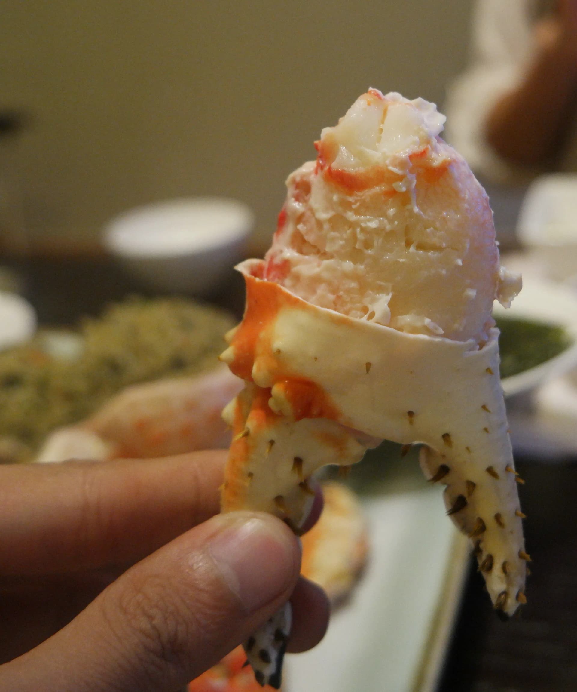 Mano sujetando un trozo enorme de carne de la pinza gigante del cangrejo real ya pelada | 하이제이에스비