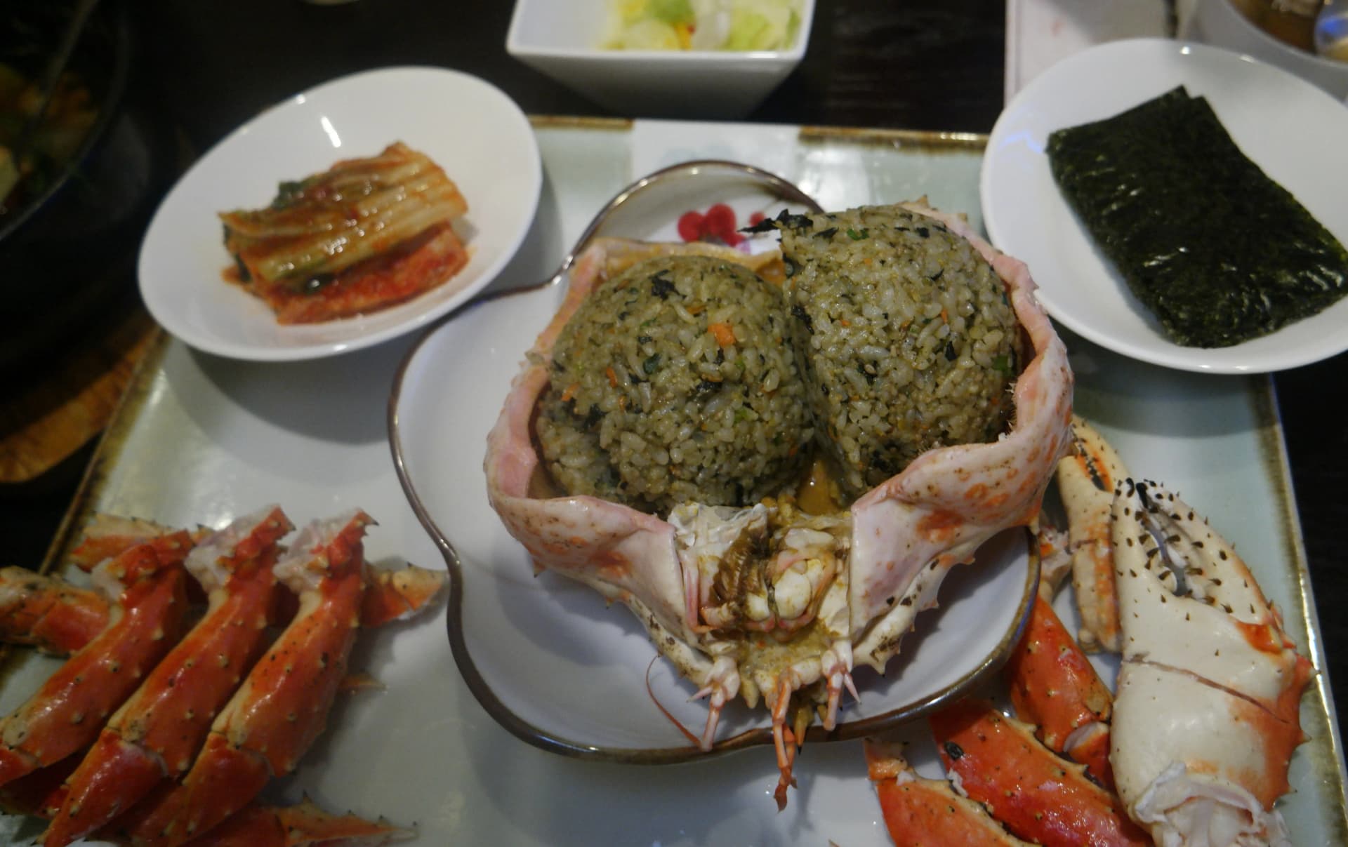 Arroz frito en caparazón de cangrejo real moldeado en bolitas redondas servido con kimchi y alga nori al lado | 하이제이에스비
