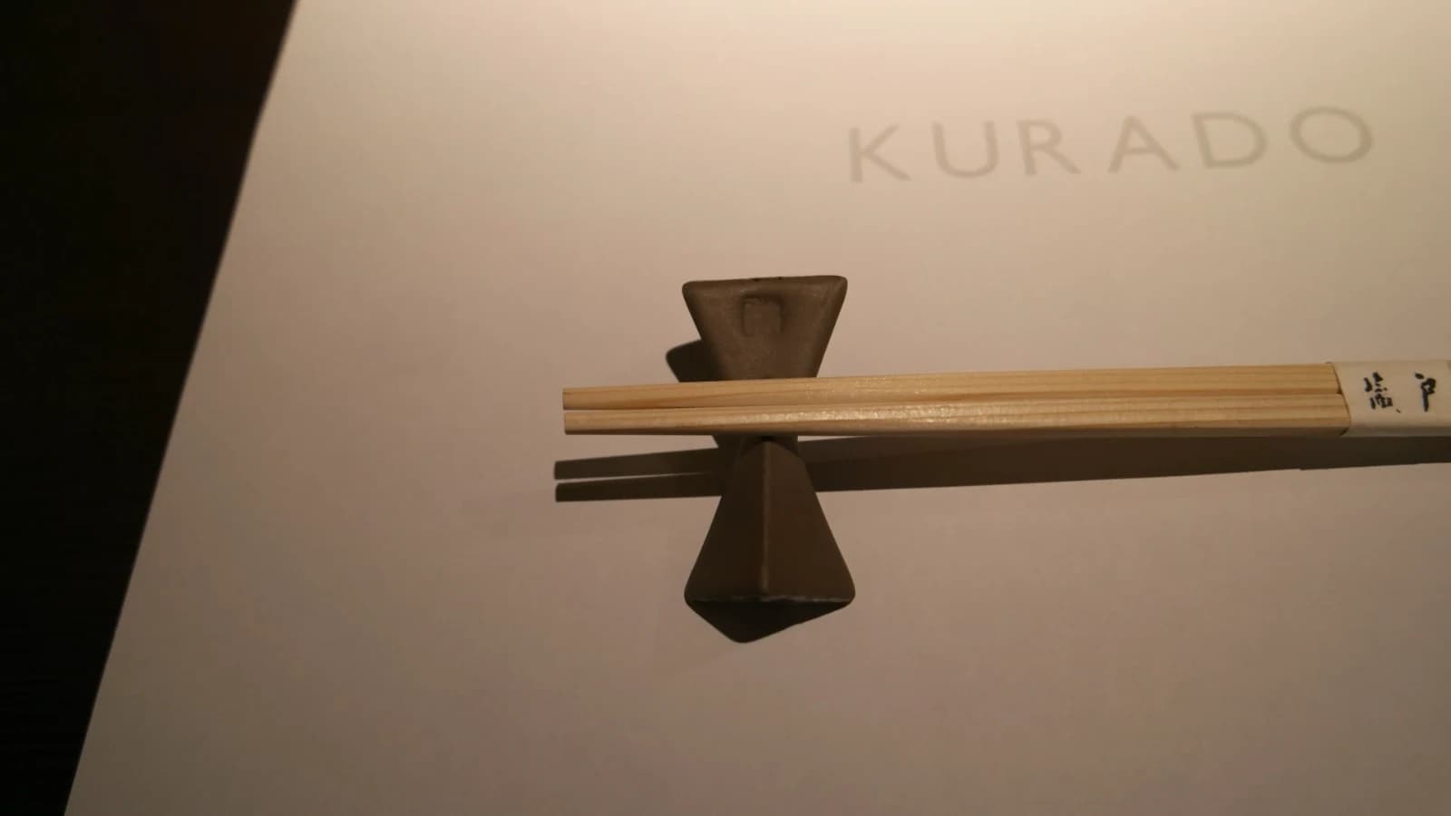 Couverts de Kurado, baguettes en bois sur repose-baguette en céramique avec set de table blanc au logo argenté