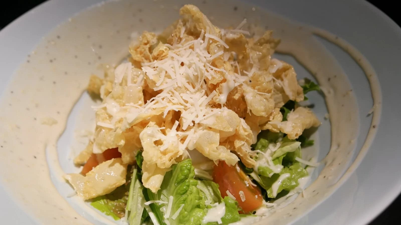 Serveur saupoudrant des miettes de tempura croustillantes sur la salade en cours de finition