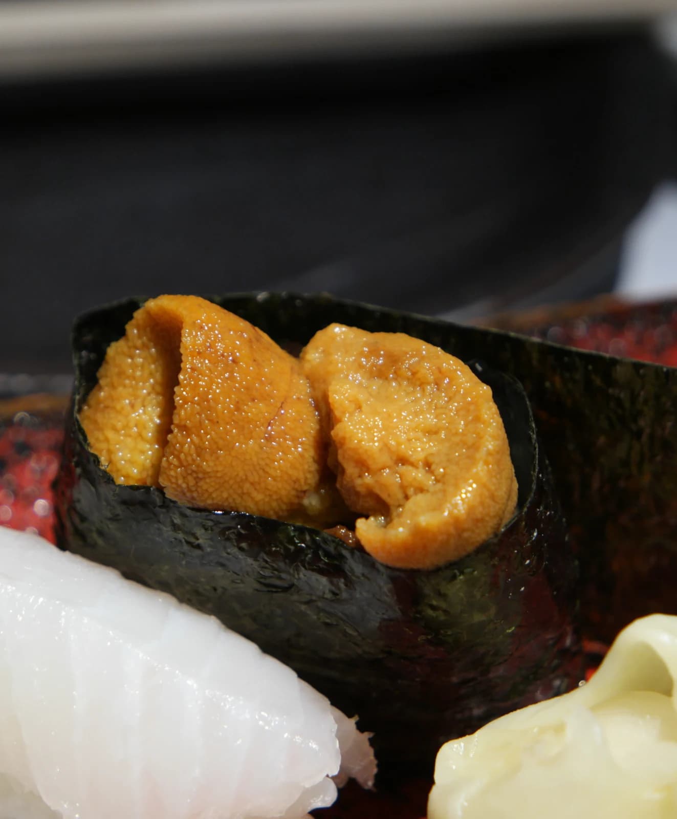 Gunkan-maki à l'oursin, riz entouré de nori avec uni orange vif posé dessus
