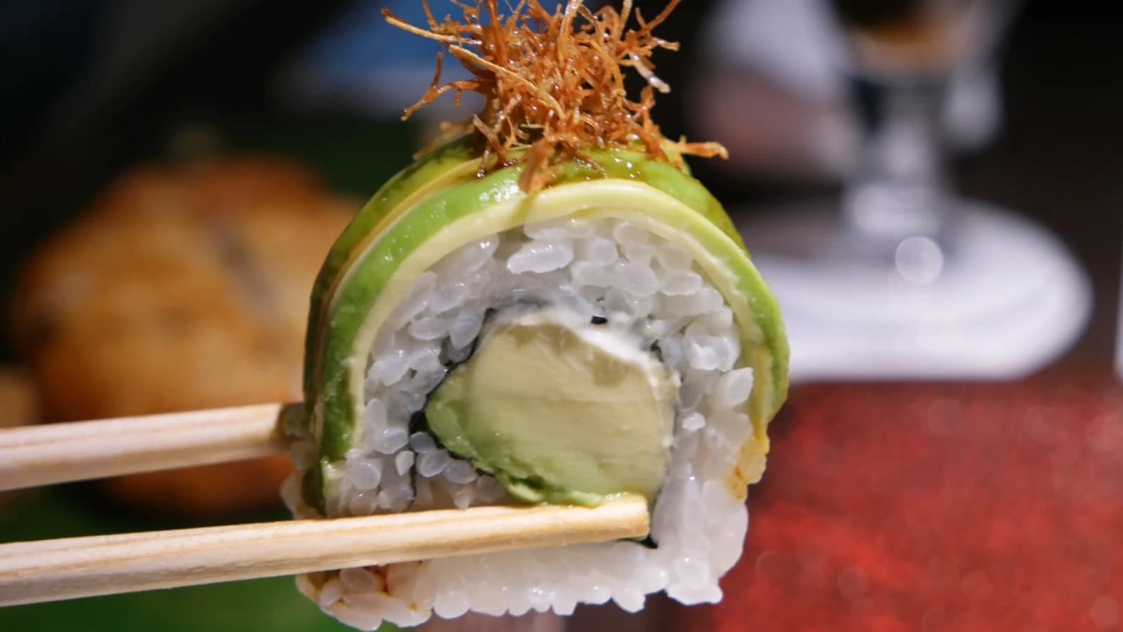 Maki à l'avocat soulevé aux baguettes, structure intacte avec garniture crémeuse visible
