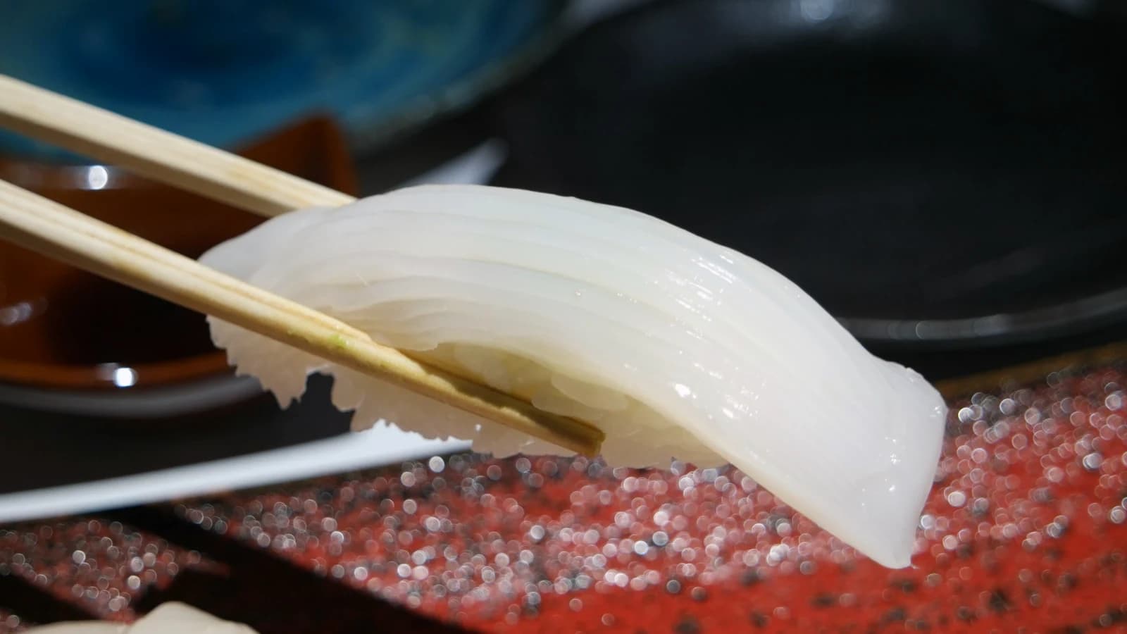 Gros plan sur sushi de calmar translucide aux entailles fines en quadrillage régulier