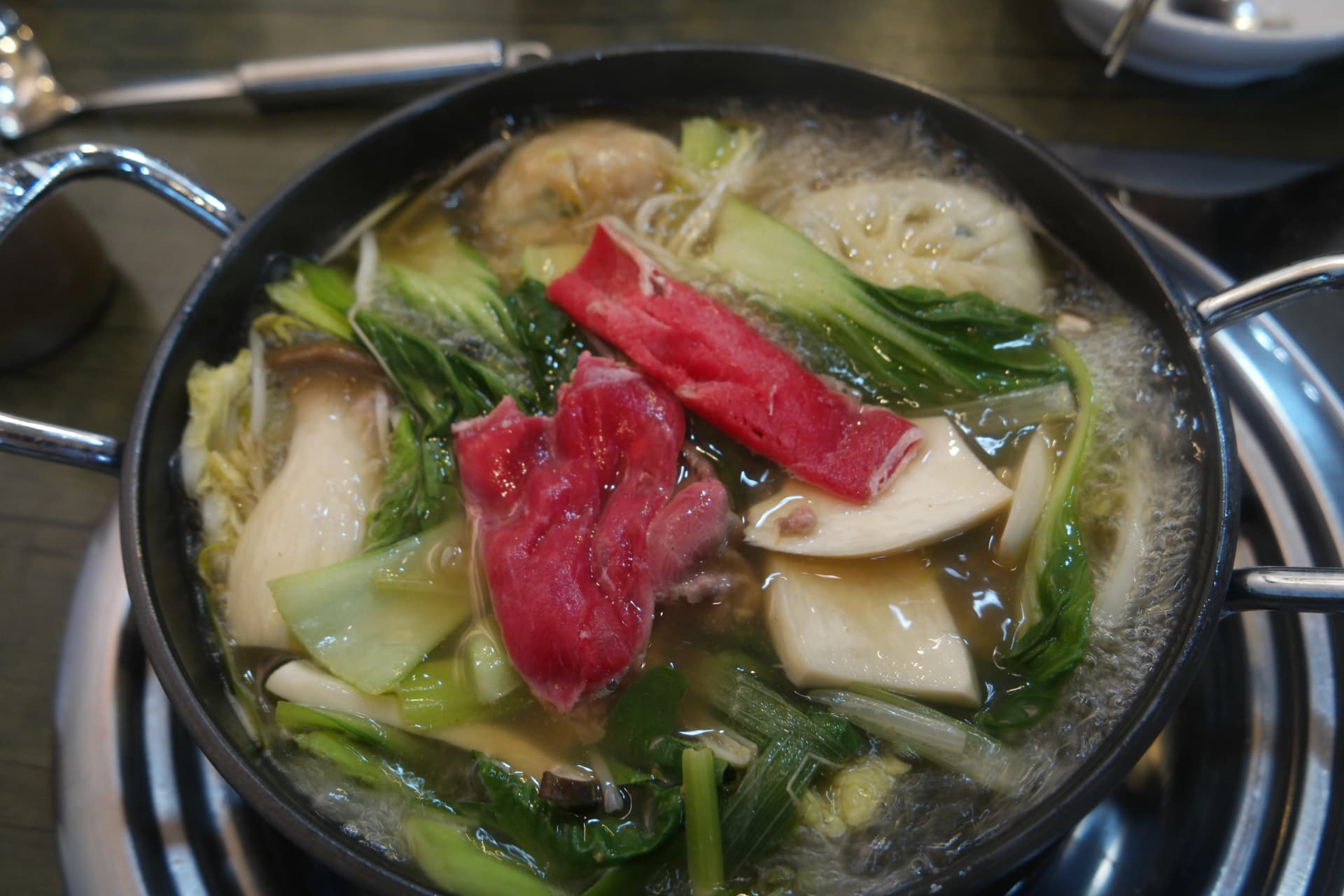 만두와 야채가 끓고 있는 전골에 소고기를 추가하는 모습 | 하이제이에스비