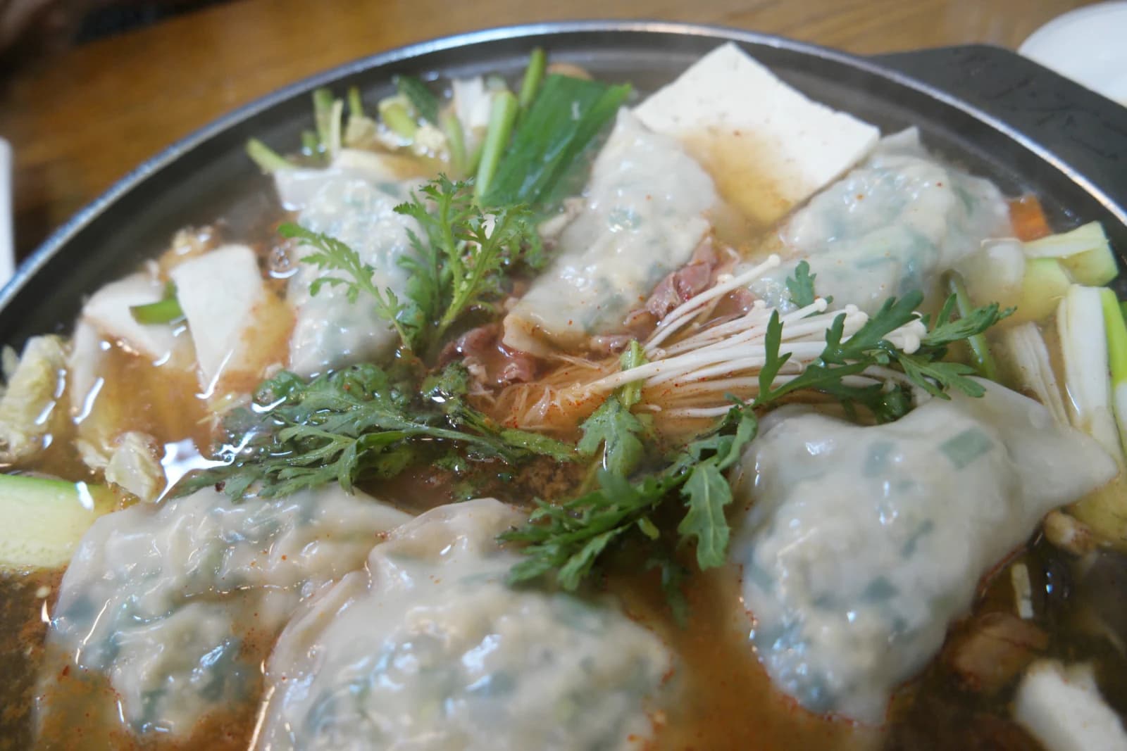Mandu jeongol starting to boil — dumplings puffing up and beef cooking as the broth deepens in color