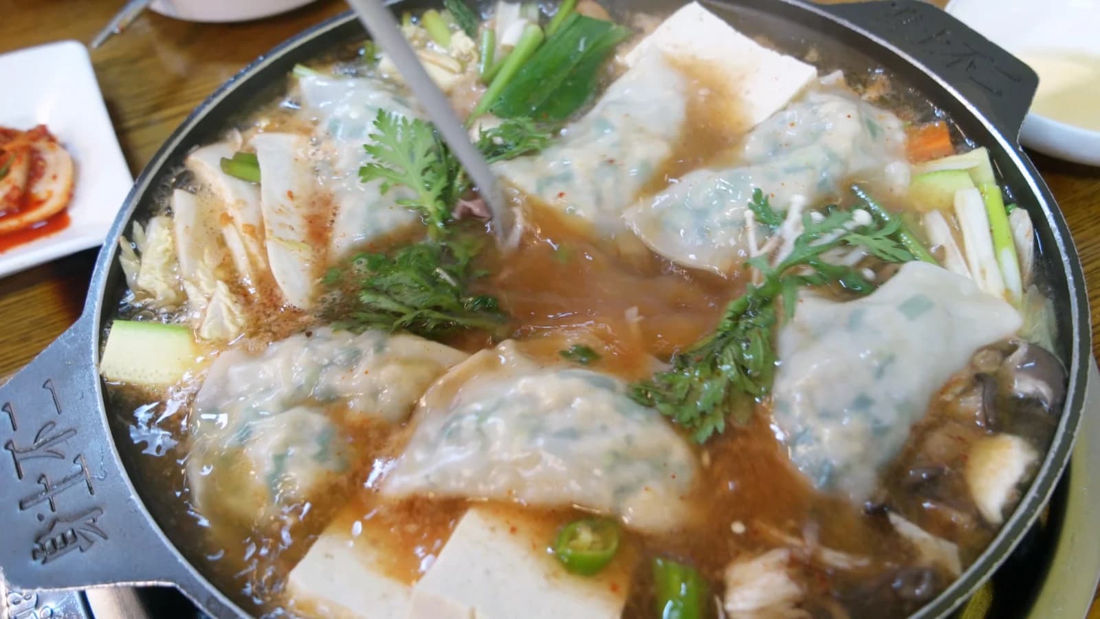 Well-simmered dumpling hot pot — ladle resting in thick, dark amber broth with fully cooked ingredients