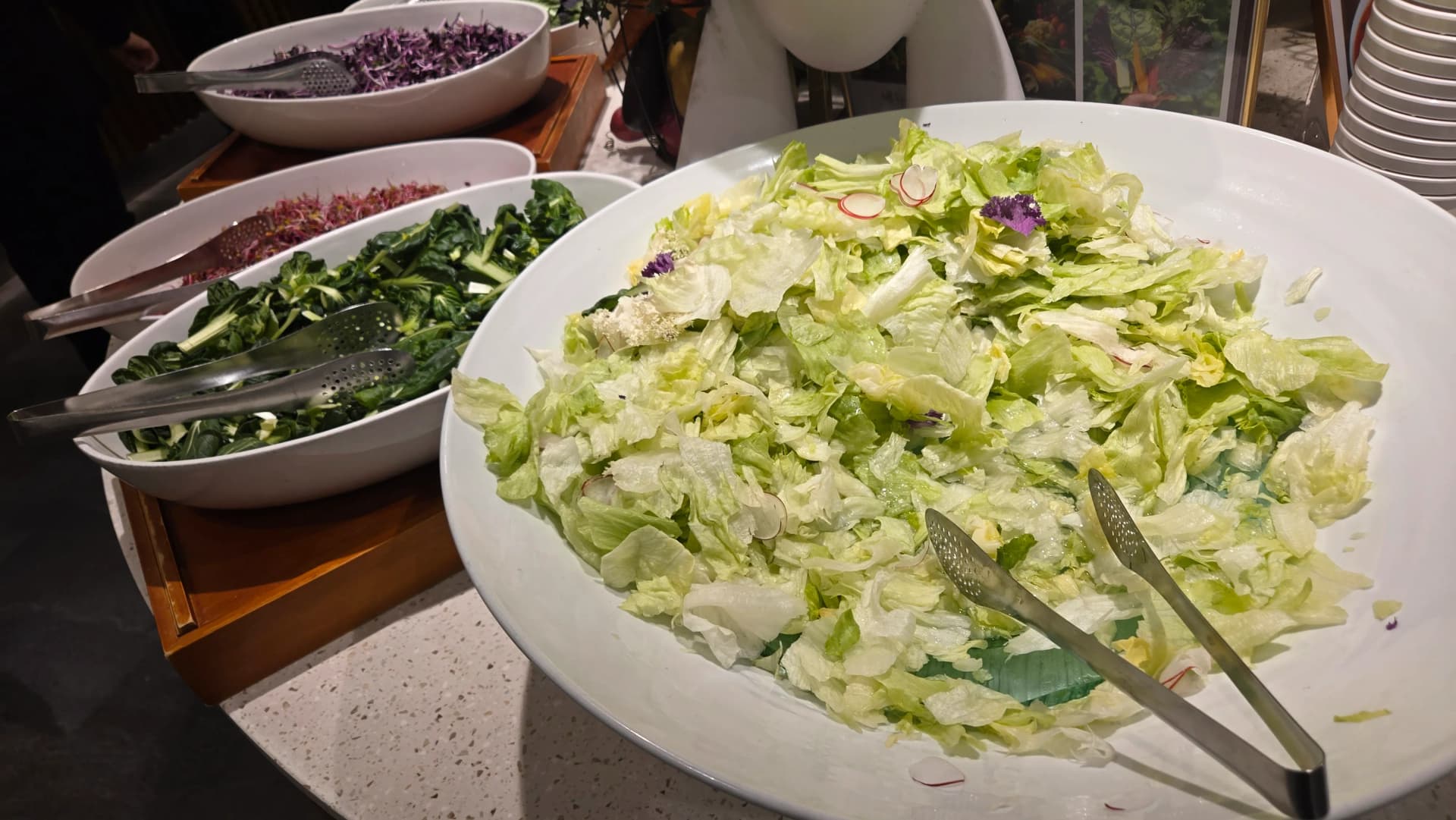Baa ya saladi ya buffet, lettuce, spinachi na kabichi nyekundu katika bakuli kubwa zilizopambwa na radishi na maua ya chakula | 하이제이에스비