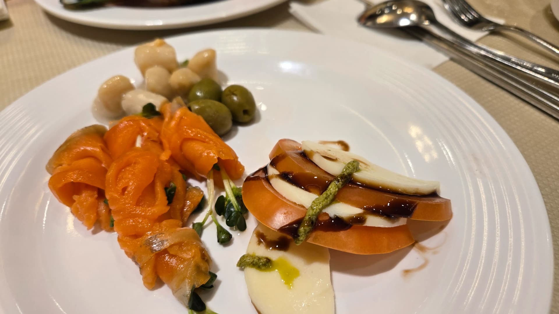 Sahani ya appetizer, lax ya kuvuta moshi iliyoviringwa kama waridi na caprese, zeituni na mozzarella ndogo, upangaji wa kifahari | 하이제이에스비