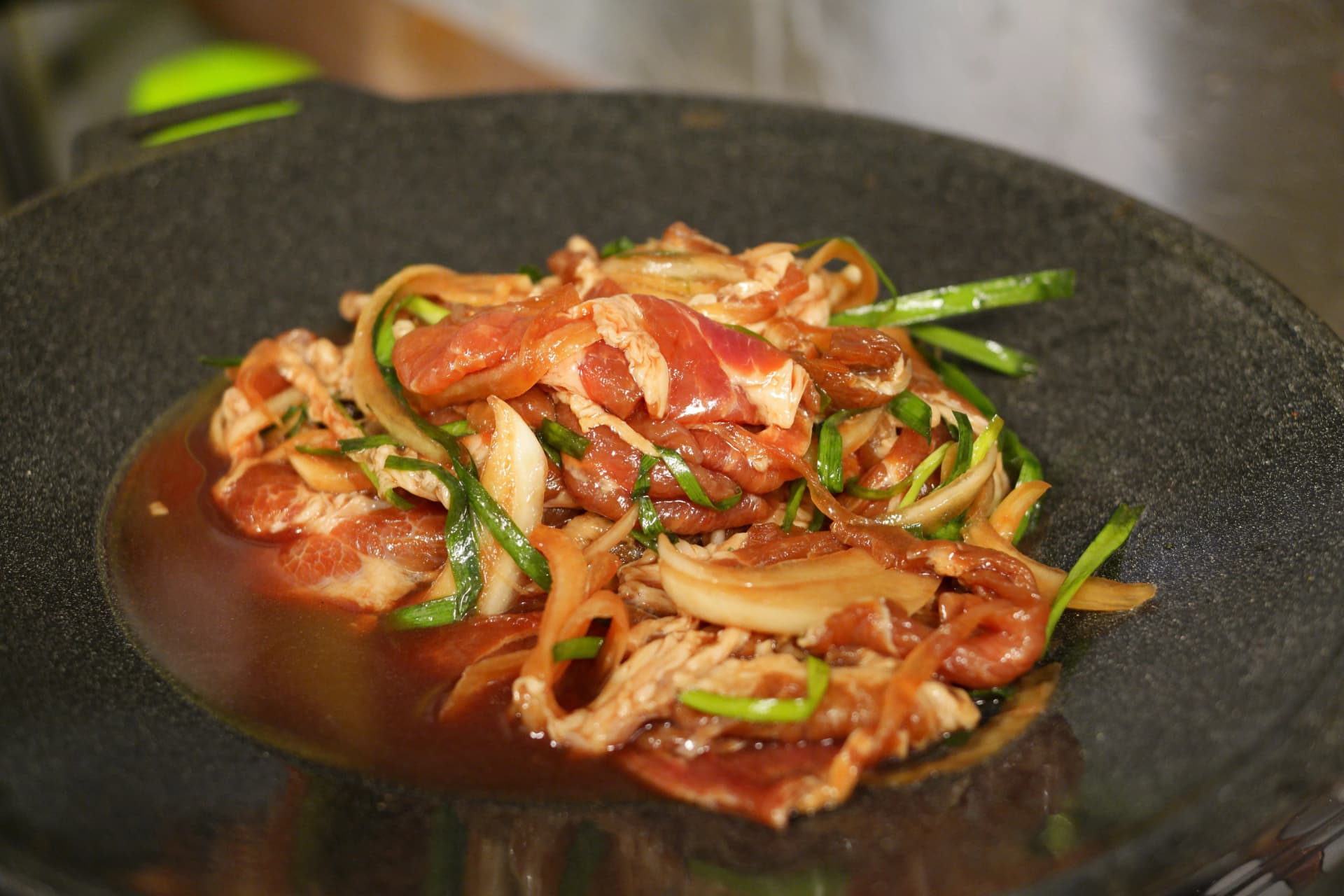 Jumulleok ya nguruwe yenye mchuzi wa soya juu ya sahani ya chuma, pamoja na vitunguu na vitunguu maji | 하이제이에스비