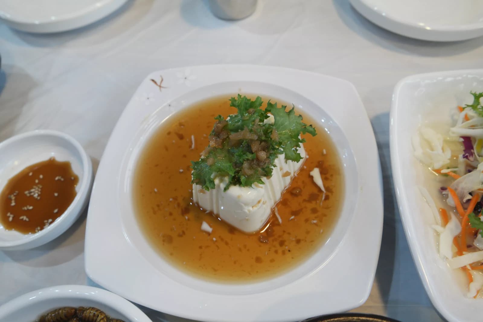 Soft silken tofu topped with scallion threads and seasoning in a soy-based sauce