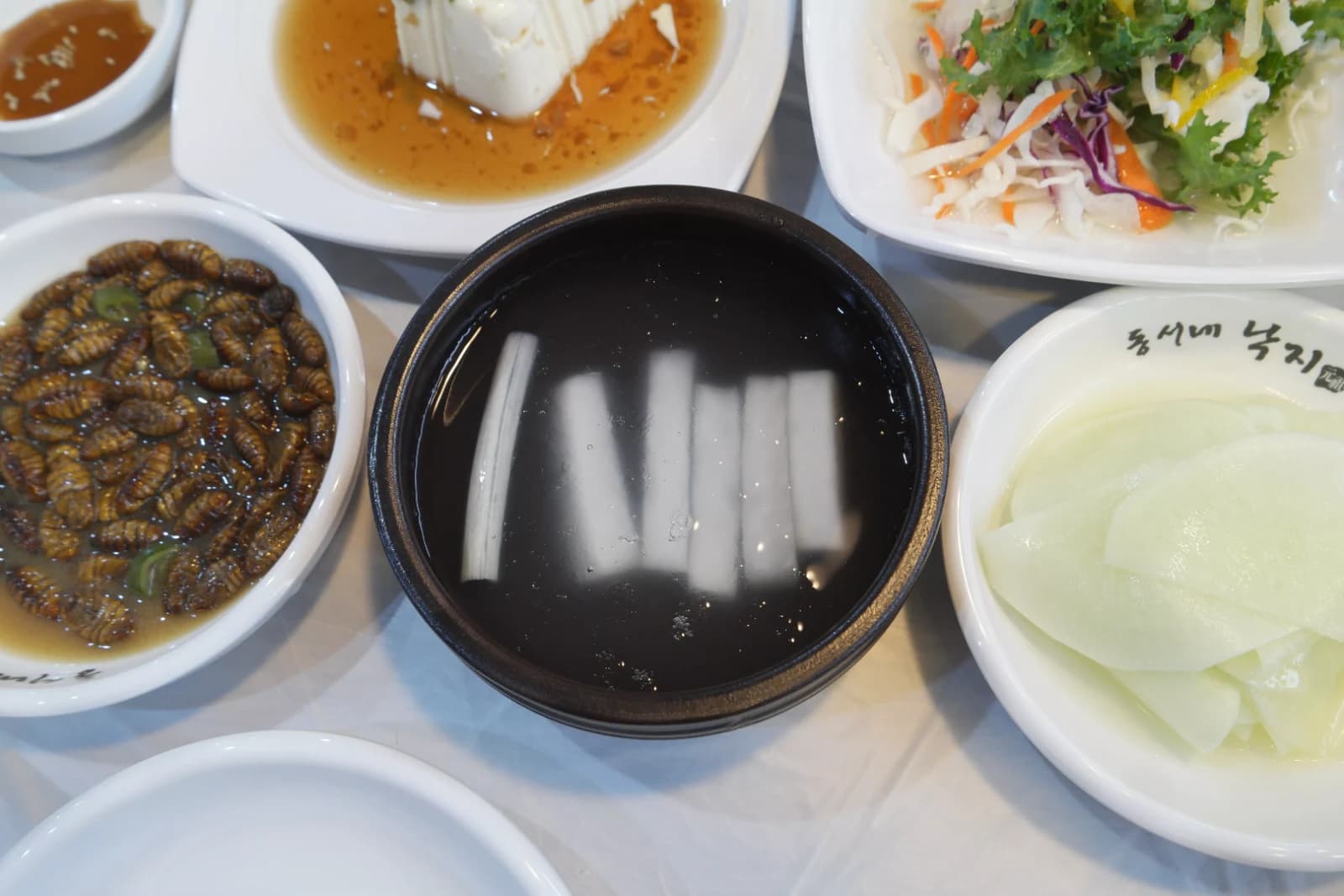 Dongchimi radish water kimchi served cold in a dark bowl with clear fermented brine