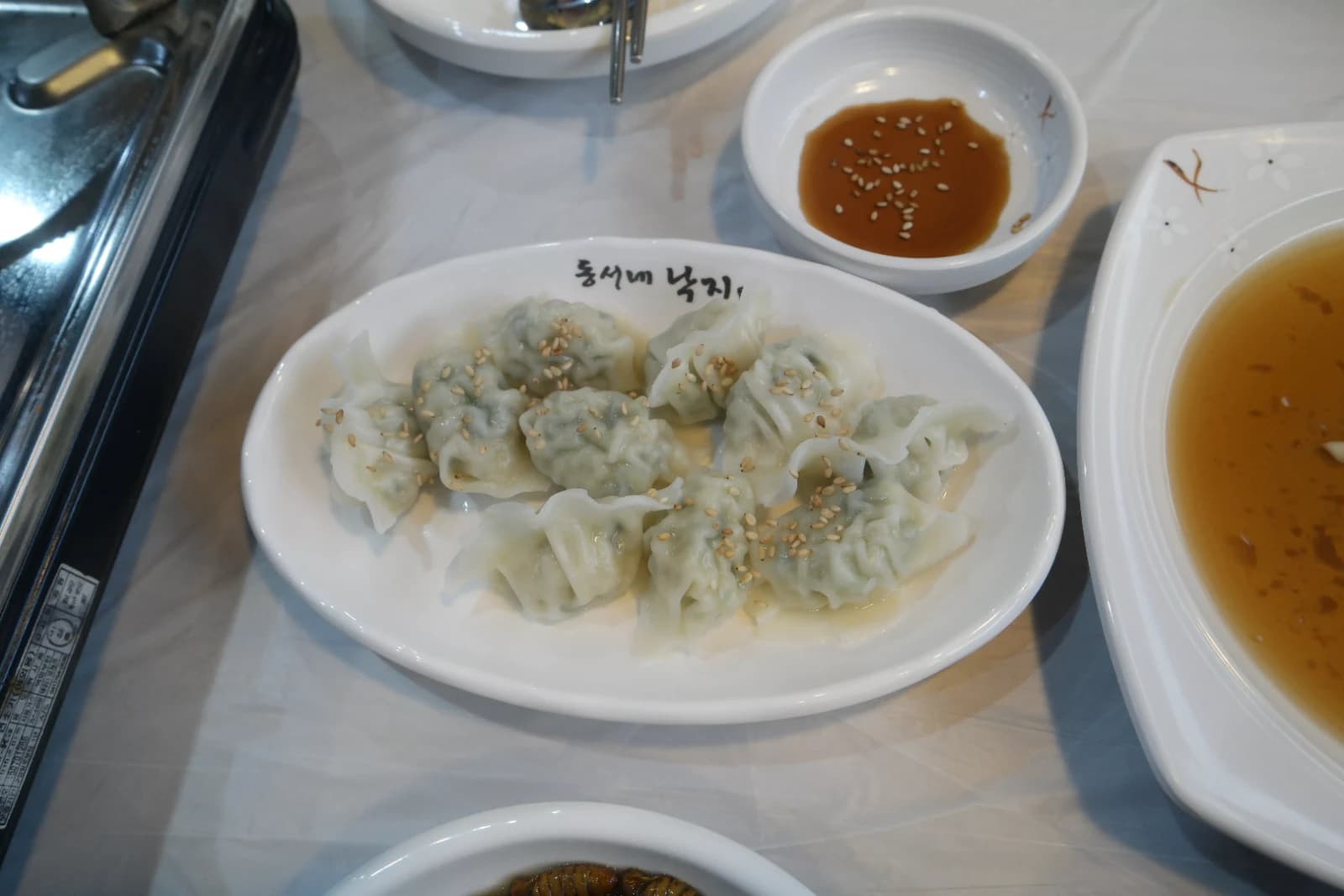 Thin-skinned boiled Korean dumplings mandu sprinkled with sesame seeds served with soy dipping sauce