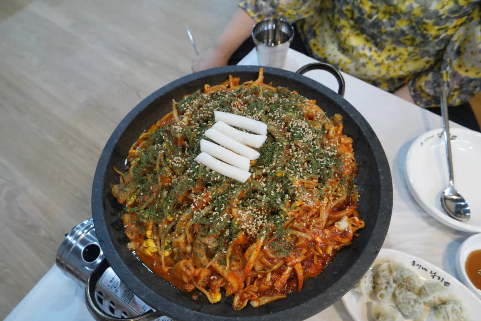 Sogopchang nakji bokkeum spicy octopus and beef intestine stir-fry piled high on a sizzling stone plate topped with seaweed flakes and sesame seeds