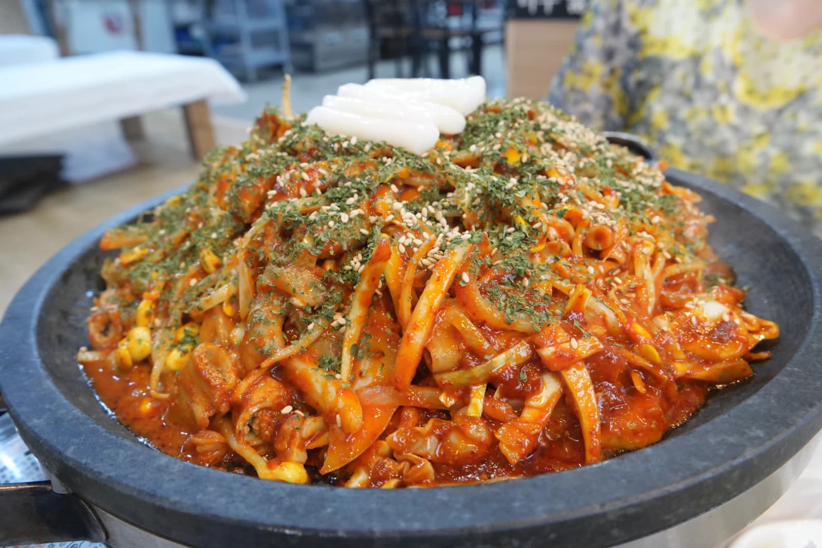 Side view of sogopchang nakji bokkeum mounded high on a stone plate showing the volume of the spicy stir-fry