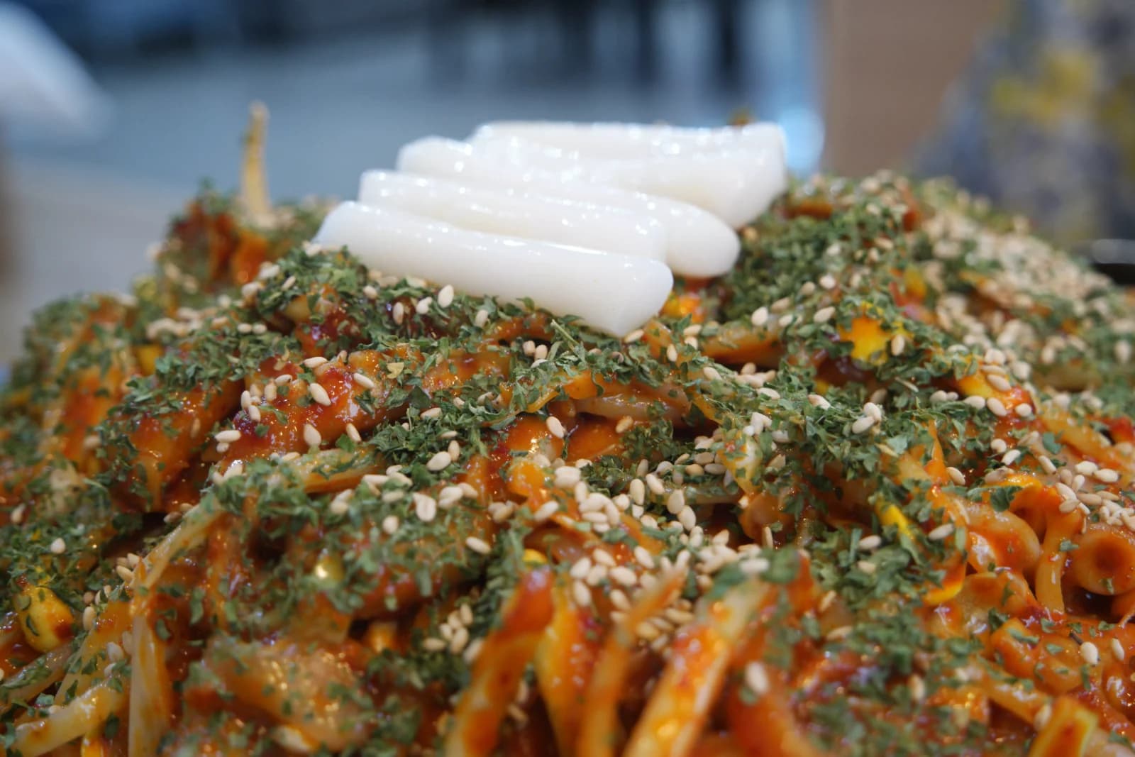 Close-up of garaetteok rice cakes seaweed flakes and sesame seeds topping the spicy octopus intestine stir-fry