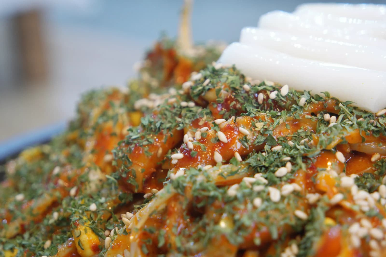 Extreme close-up of sogopchang nakji bokkeum showing octopus tentacles sesame seeds seaweed and rice cakes
