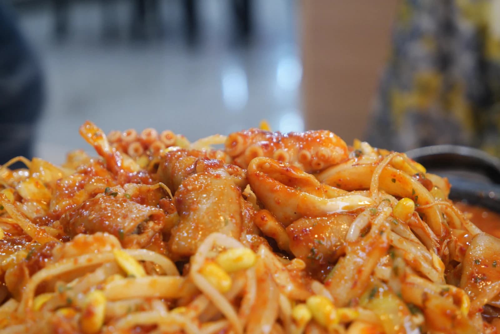 Close-up of octopus tentacles with visible suckers and sauce-glazed beef intestine pieces with bean sprouts