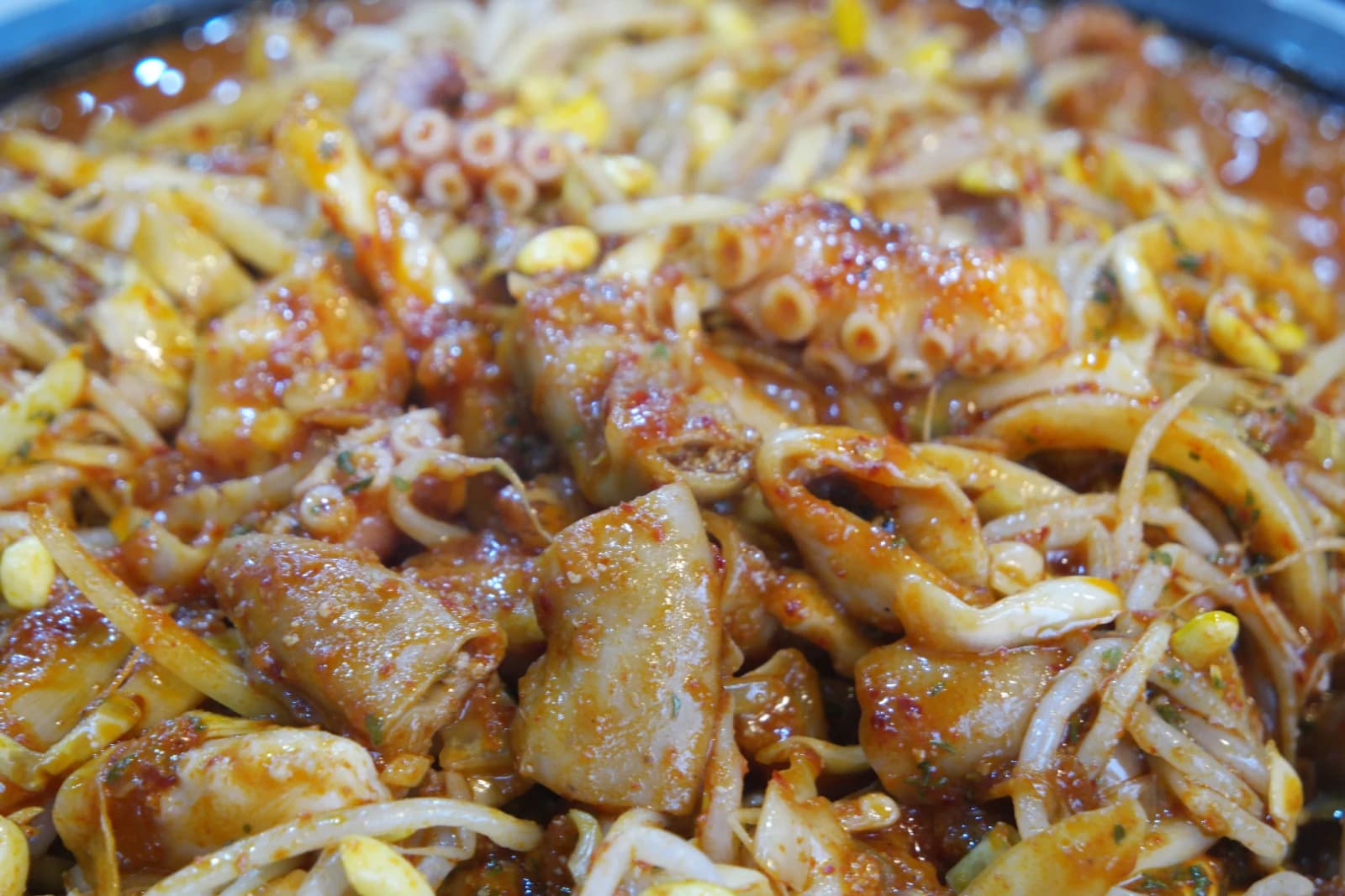 Well-mixed sogopchang nakji bokkeum with sauce fully absorbed showing cross-section of beef intestine and wilted bean sprouts
