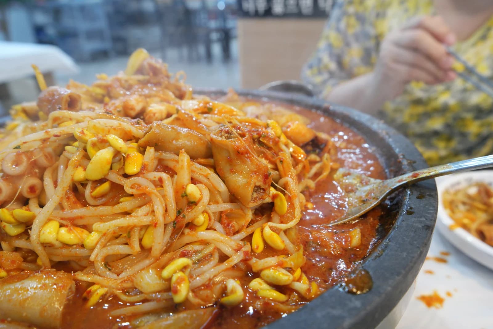 Spicy red broth pooled at the bottom of the stone plate with remaining bean sprouts and softened rice cakes after eating sogopchang nakji bokkeum