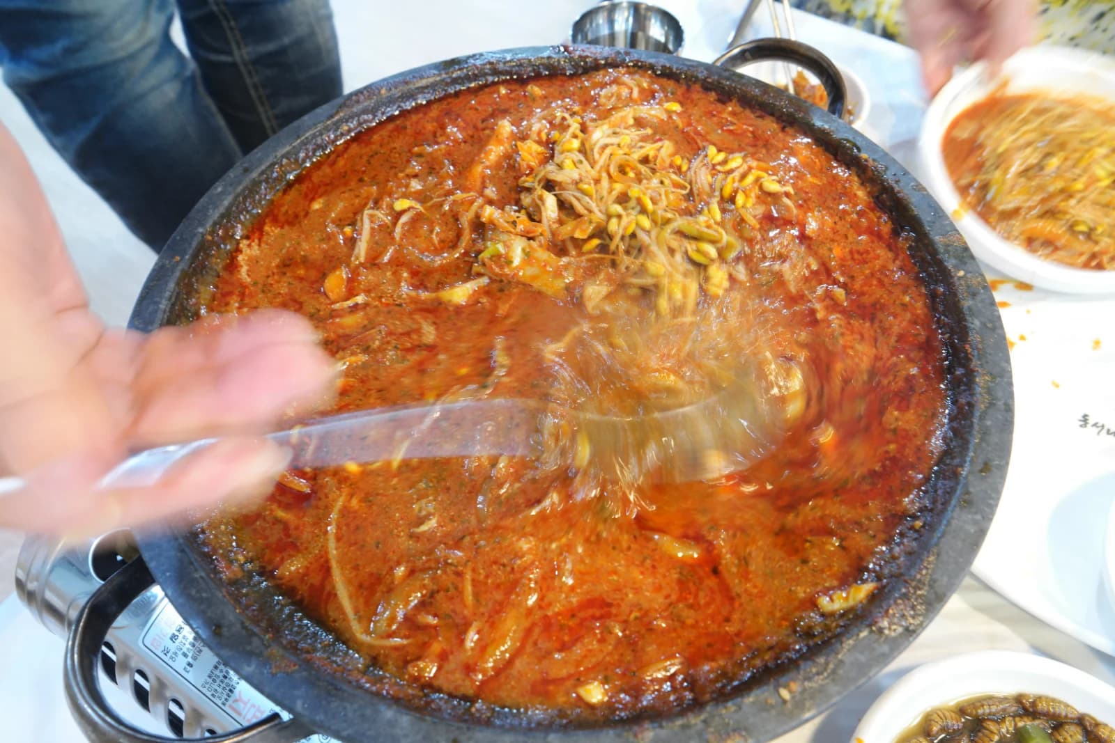 Empty stone plate with remaining red spicy broth ready to be turned into fried rice after sogopchang nakji bokkeum