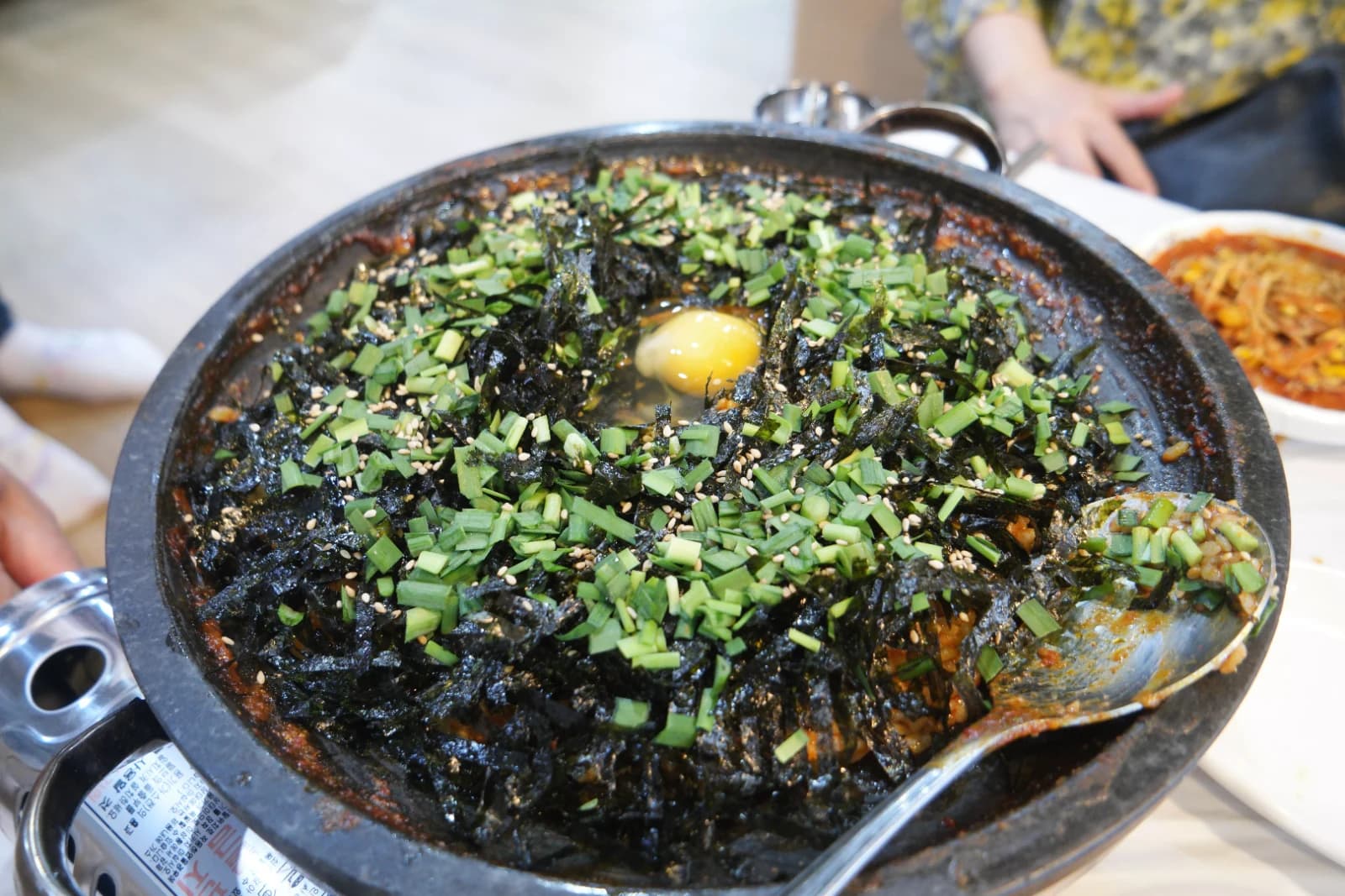 Korean fried rice bokkeum-bap made from leftover sogopchang nakji bokkeum sauce topped with seaweed flakes chives and a raw egg yolk
