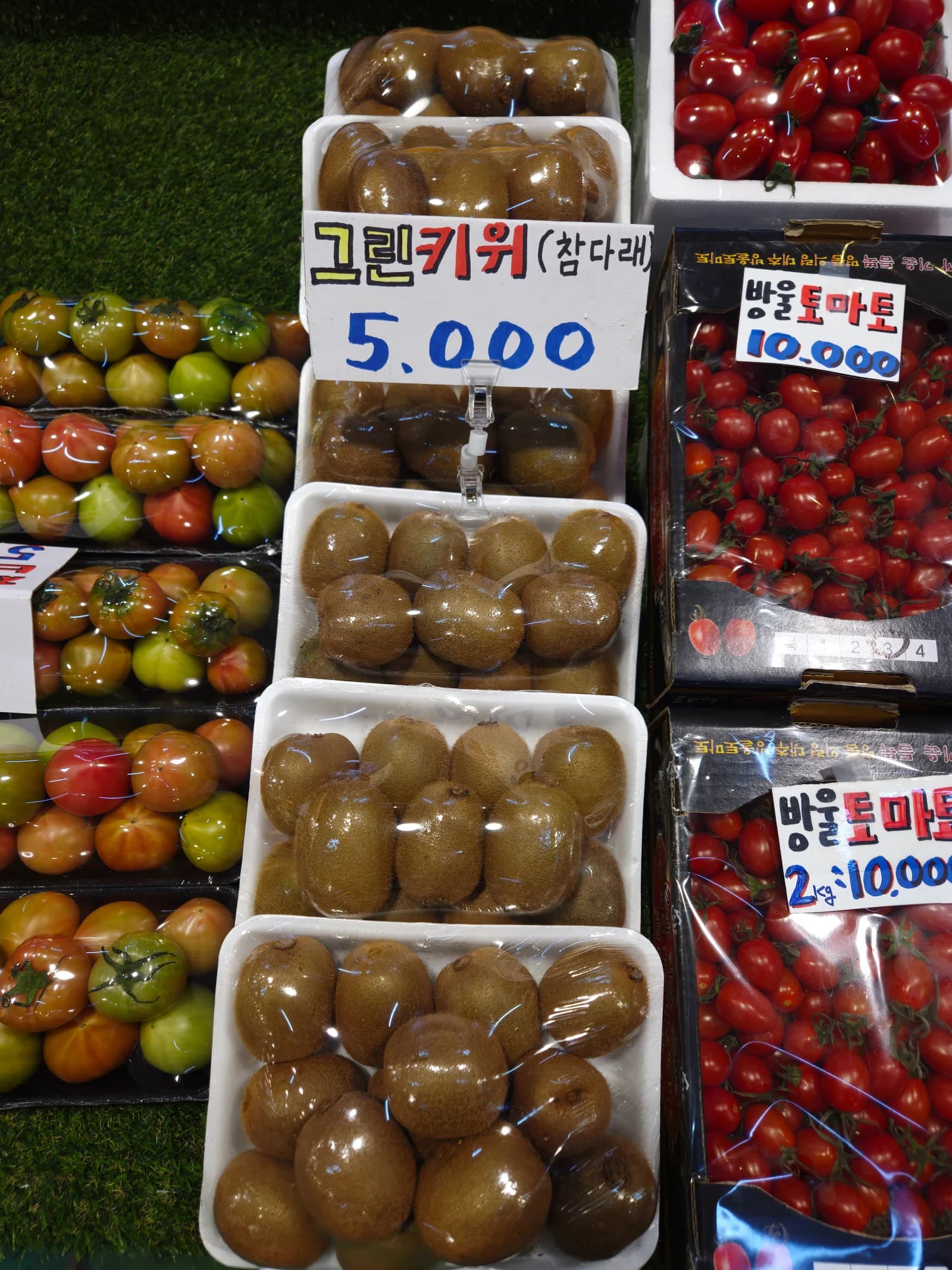 그린키위 한 팩 5000원과 방울토마토 2kg 10000원, 대저토마토가 함께 보이는 진열대