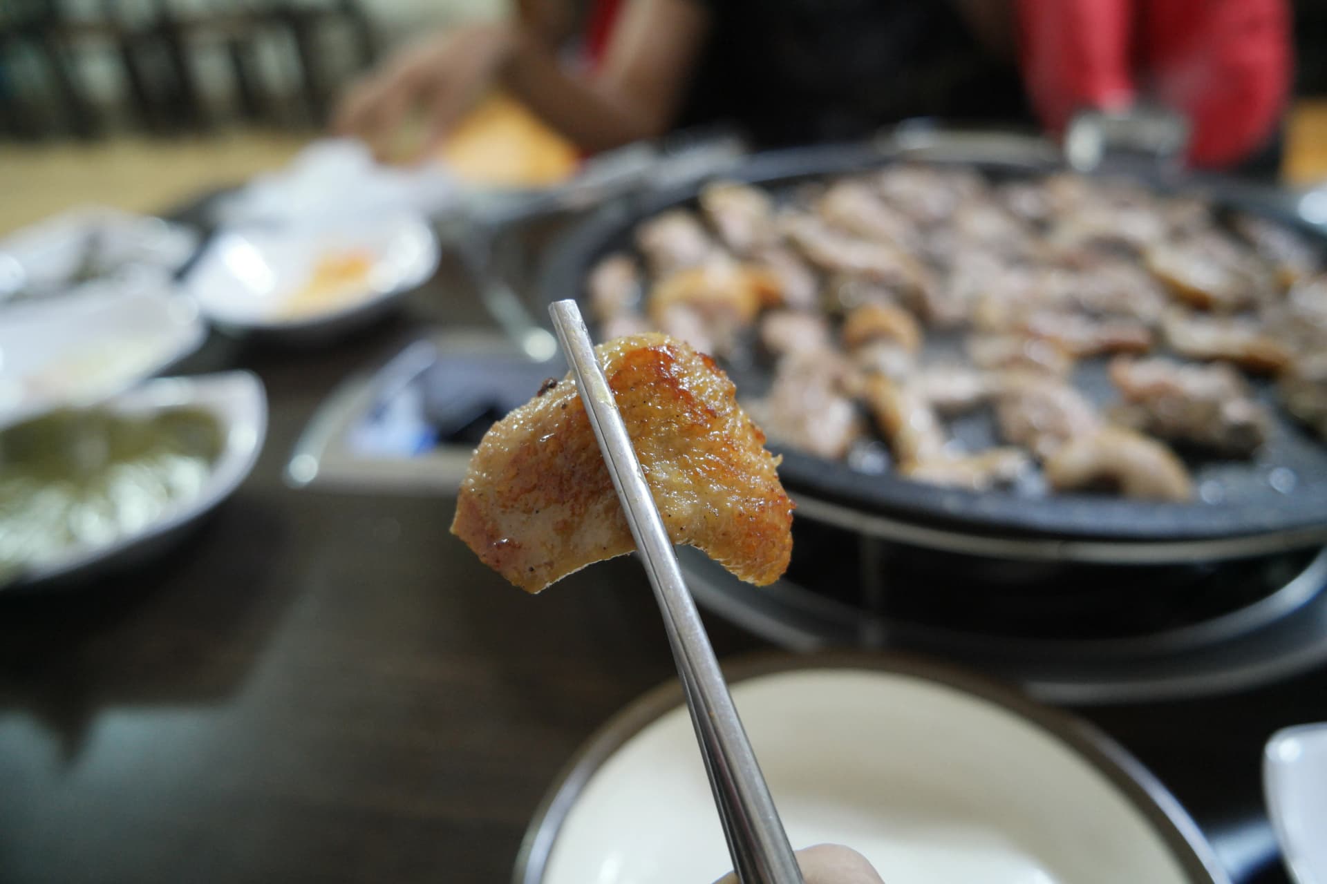 Sumpit mengangkat sepotong bebek panggang kulit krispy keemasan dengan irisan juicy | 하이제이에스비