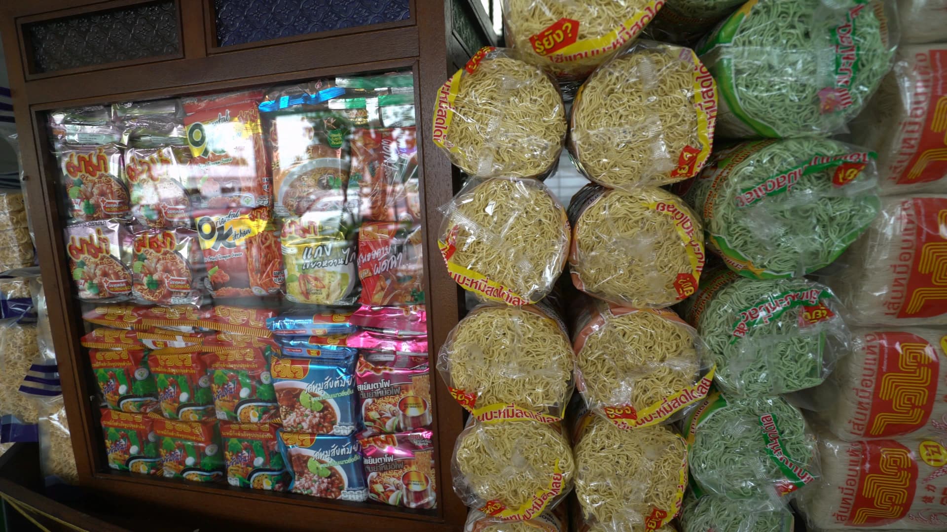 Thai gas station restaurant display shelf stacked with instant noodles and fresh noodle varieties