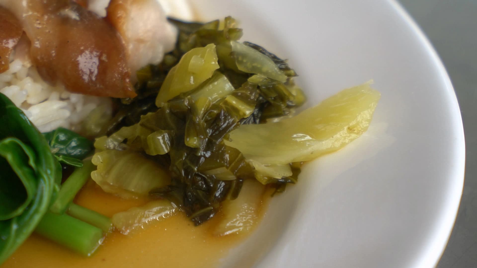 Spooning up Thai braised pork leg rice showing meat and sauce mixed with jasmine rice