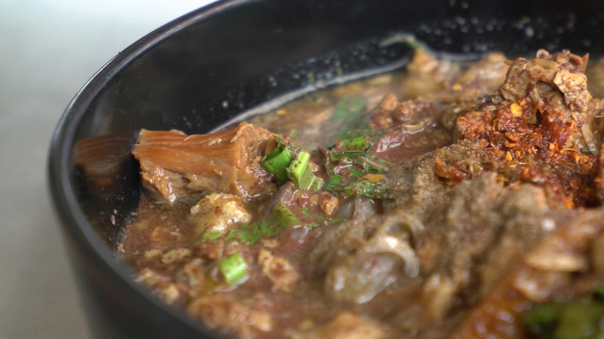Overhead view of kuay tiew nam tok showing rice noodles pork slices bean sprouts and Thai basil