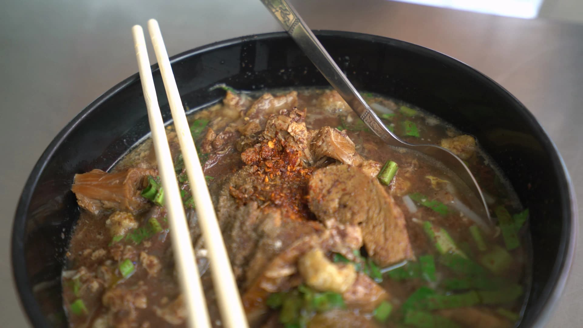 Close-up of Thai blood noodle soup kuay tiew nam tok deep brown broth texture