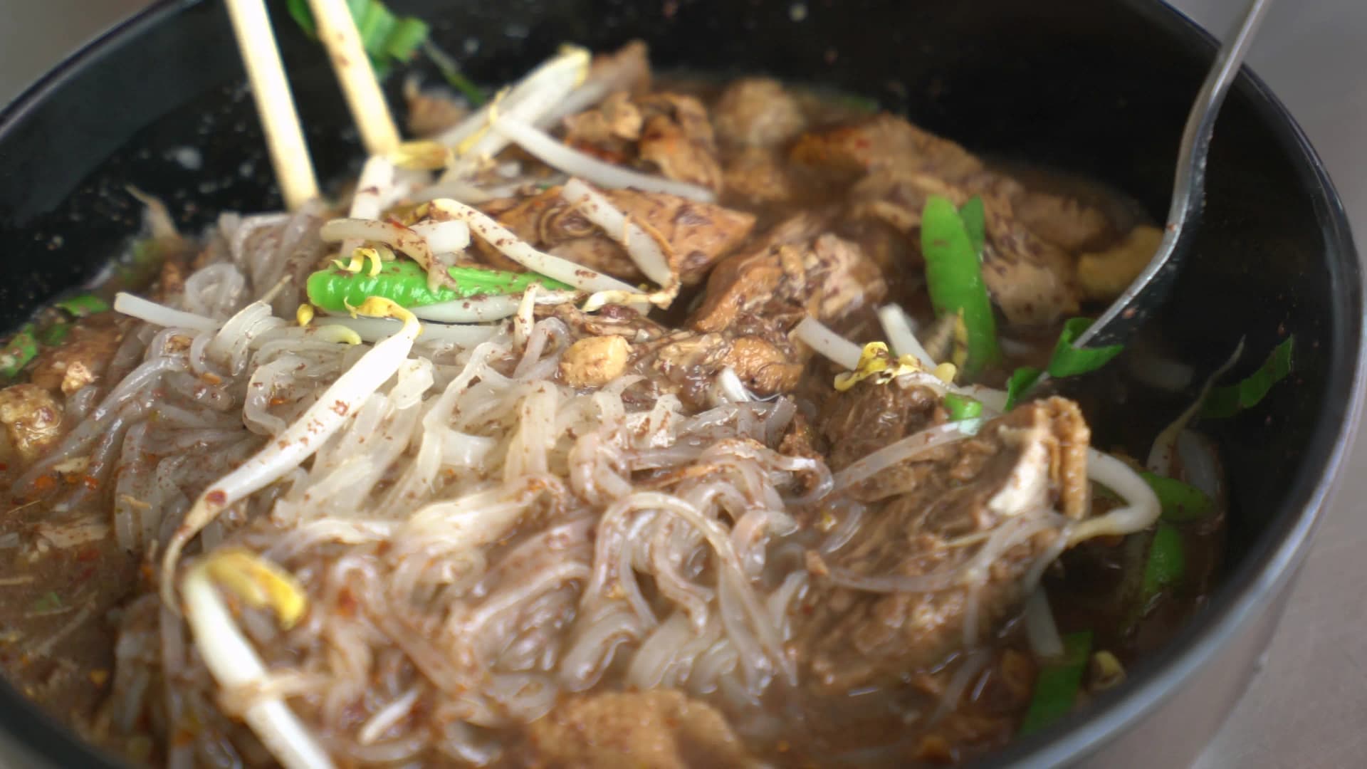 Thai blood noodle soup rice noodles in rich dark broth with crunchy bean sprouts close-up