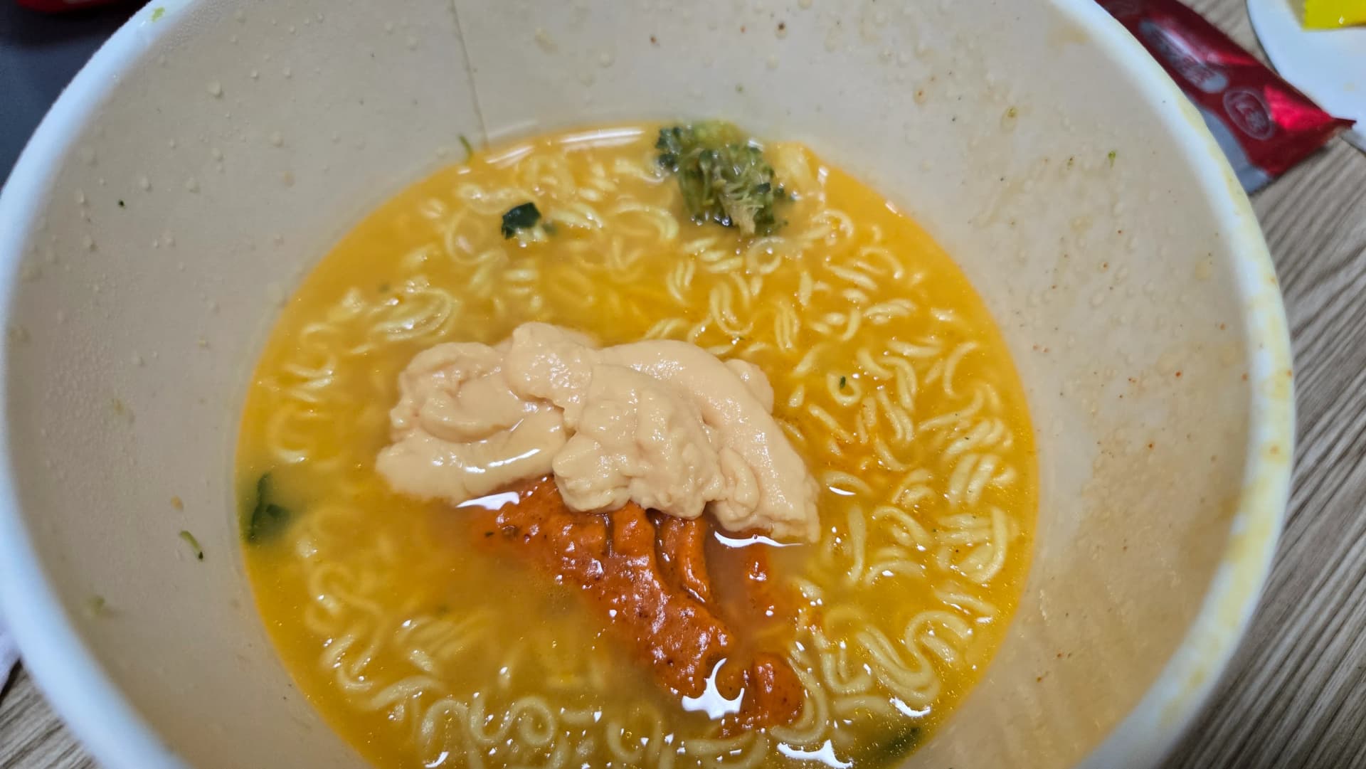 Salsa de formatge líquida de color crema sobre el brou del ramen de formatge d’Ottogi — abans de barrejar | 하이제이에스비