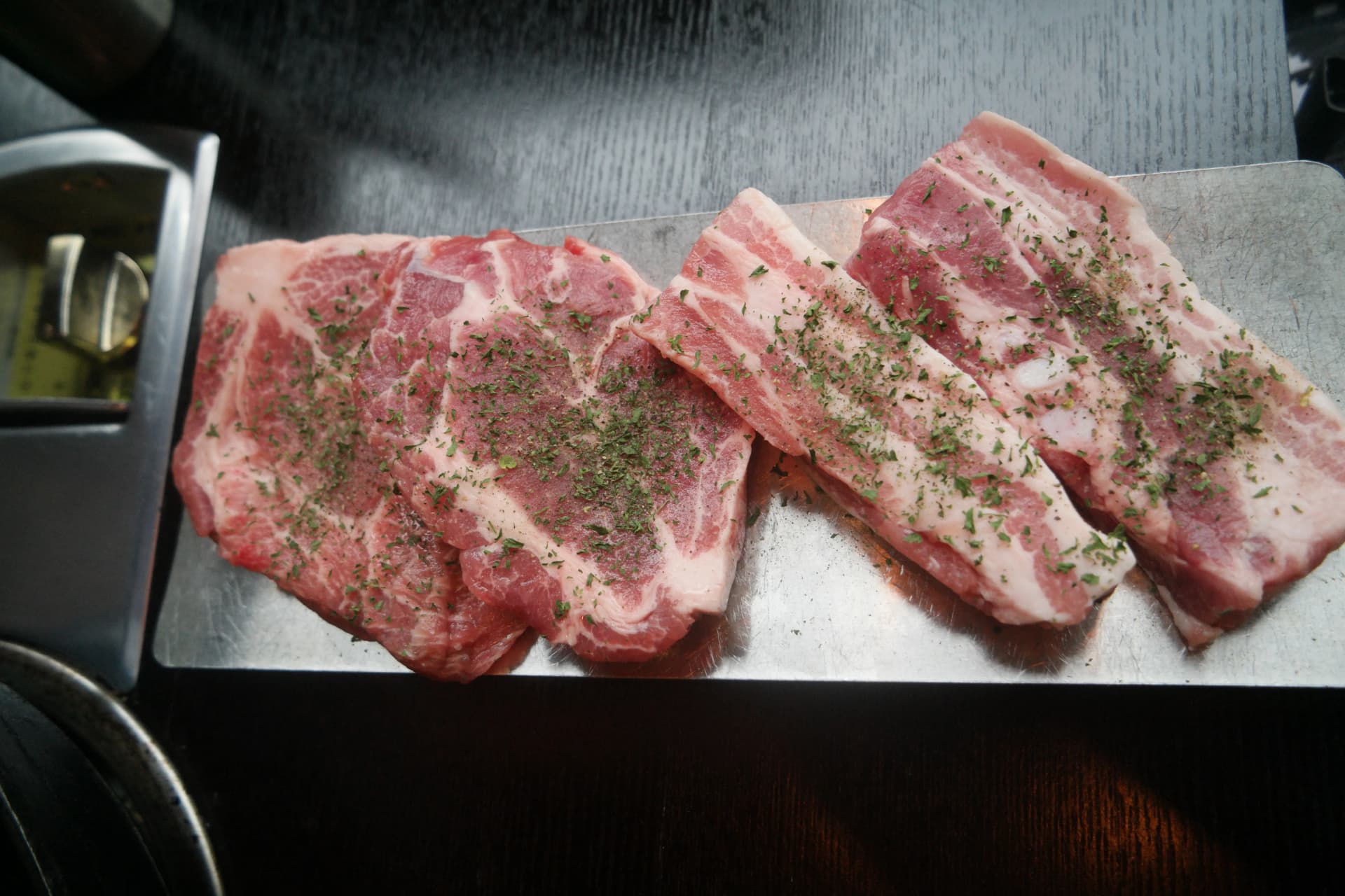 Quattro fette di pancetta coreana fresca con erbe aromatiche servite su un vassoio in un ristorante a volontà | 하이제이에스비