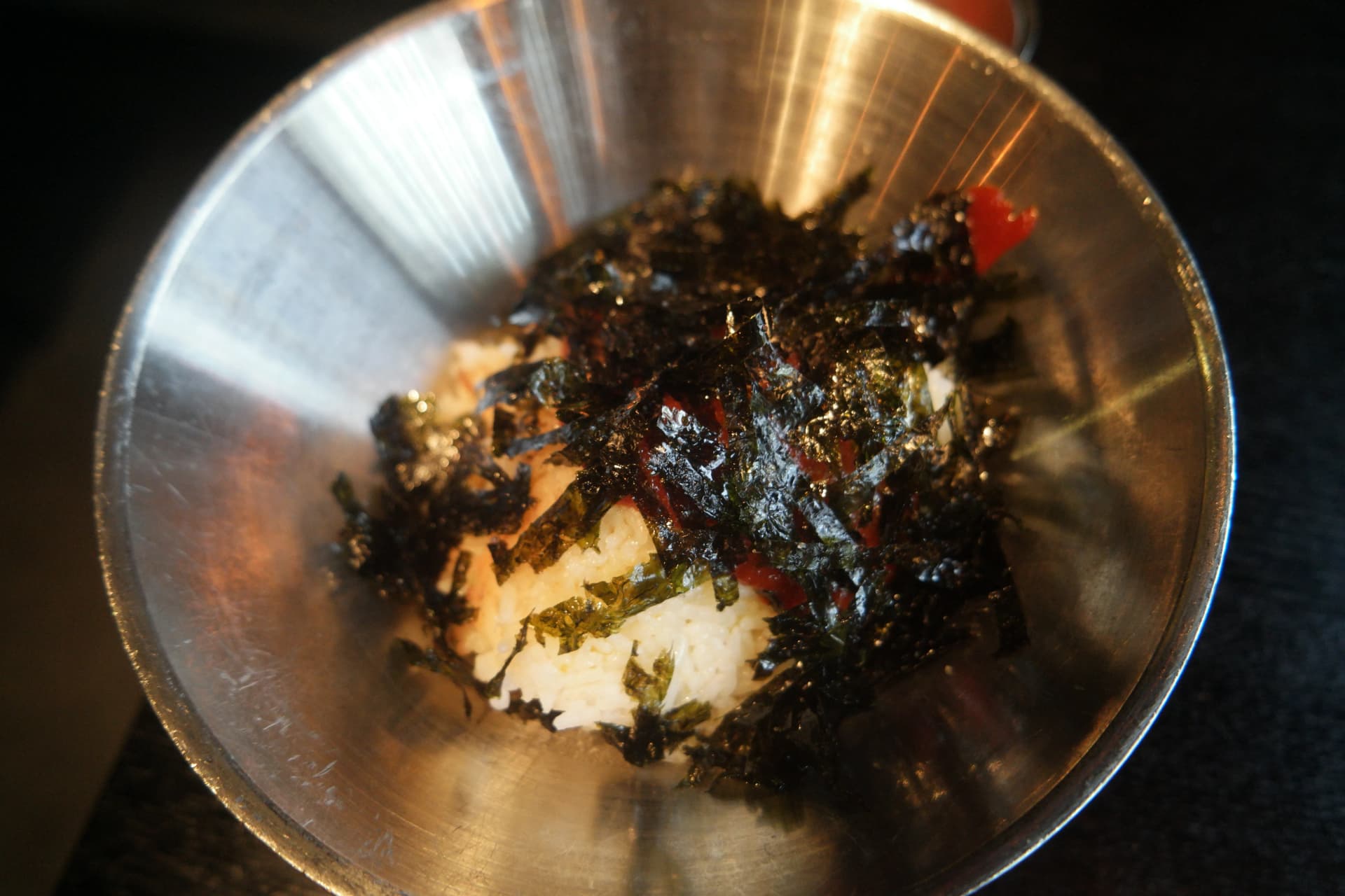Ciotola di riso bianco con abbondanti scaglie di alga nori tostata sopra servita nel ristorante coreano | 하이제이에스비