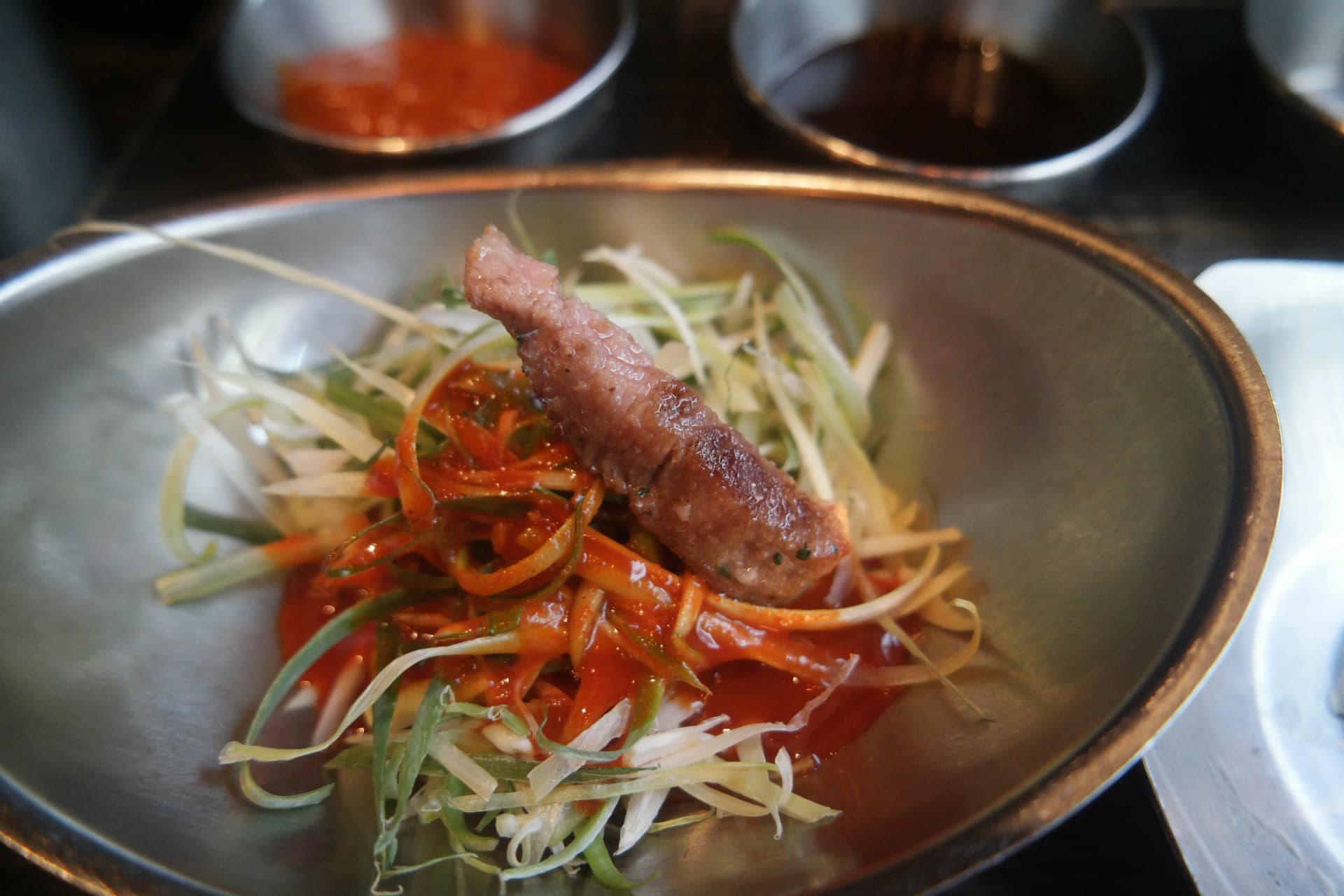 Carne grigliata adagiata sopra al cipollotto marinato a julienne nel modo tipico coreano di mangiare la carne | 하이제이에스비