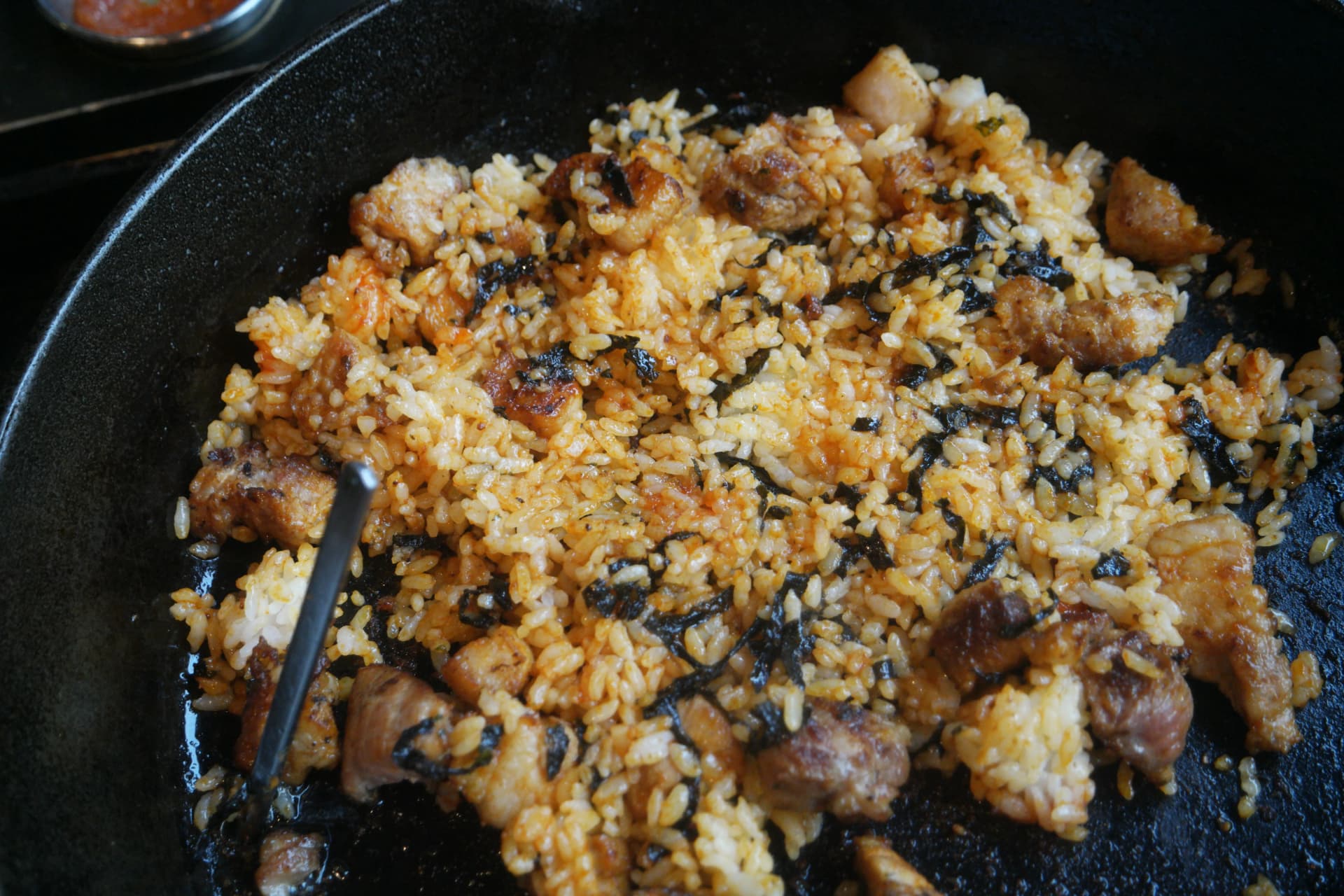 Riso fritto completato sulla padella in ghisa con pezzi di carne incorporati e chicchi croccanti e tostati | 하이제이에스비