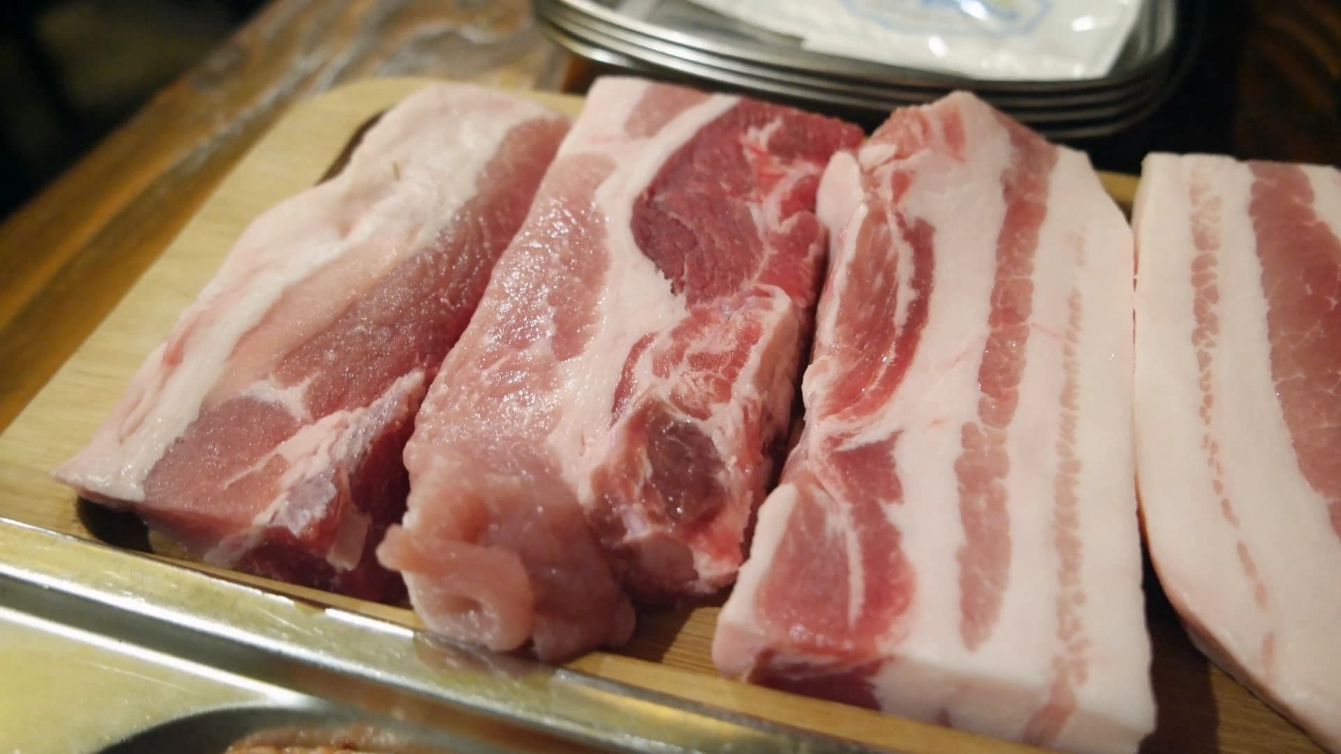 무한리필 삼겹살 전문점에서 제공되는 두툼한 생삼겹살이 나무 도마 위에 올려진 모습 | 하이제이에스비