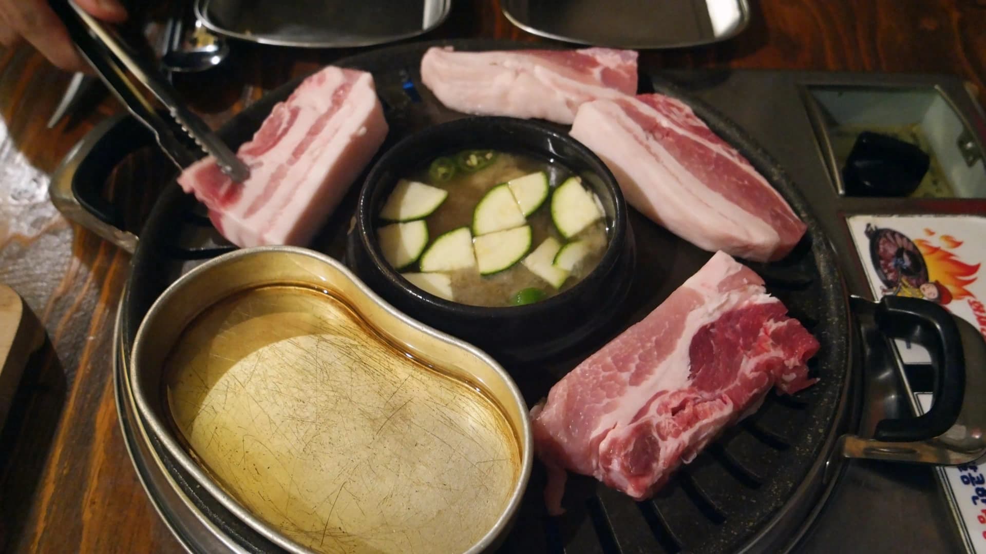 불판 위에 삼겹살 여러 점이 가득 올라가 있는 모습 - 일반 식당 기준 약 2인분 분량 | 하이제이에스비