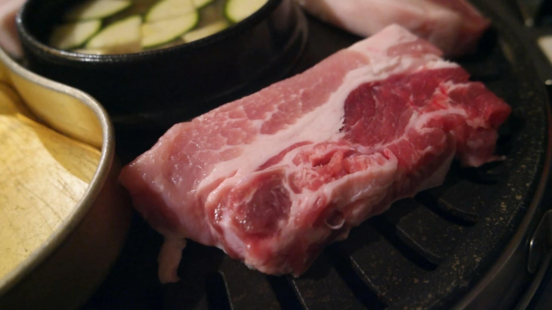 불판 위에서 아래쪽부터 익기 시작하는 생삼겹살 클로즈업 | 하이제이에스비