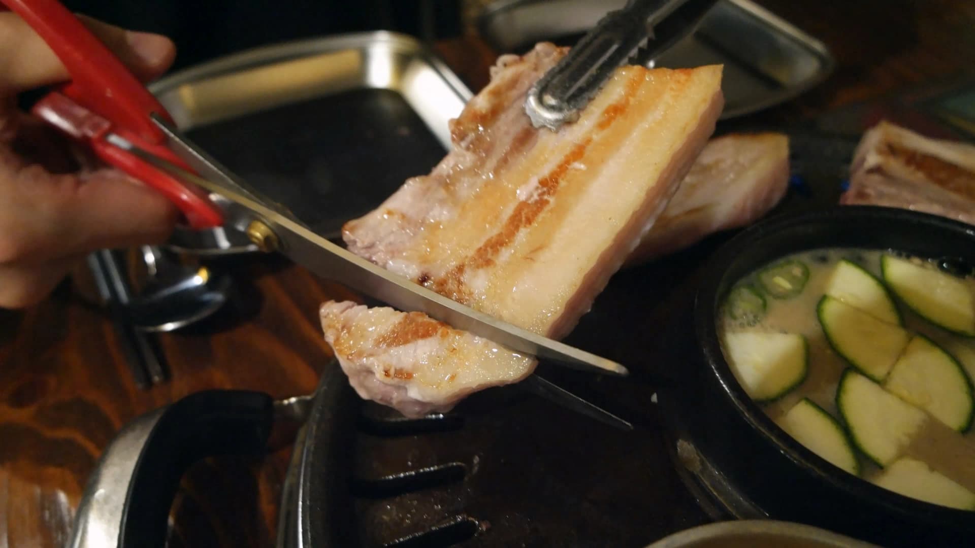 가위로 익은 삼겹살을 한입 크기로 자르는 모습 | 하이제이에스비