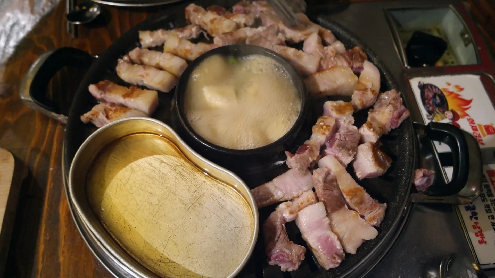 한입 크기로 잘린 삼겹살 조각들이 불판 위에 넓게 펼쳐져 골고루 익고 있는 모습 | 하이제이에스비